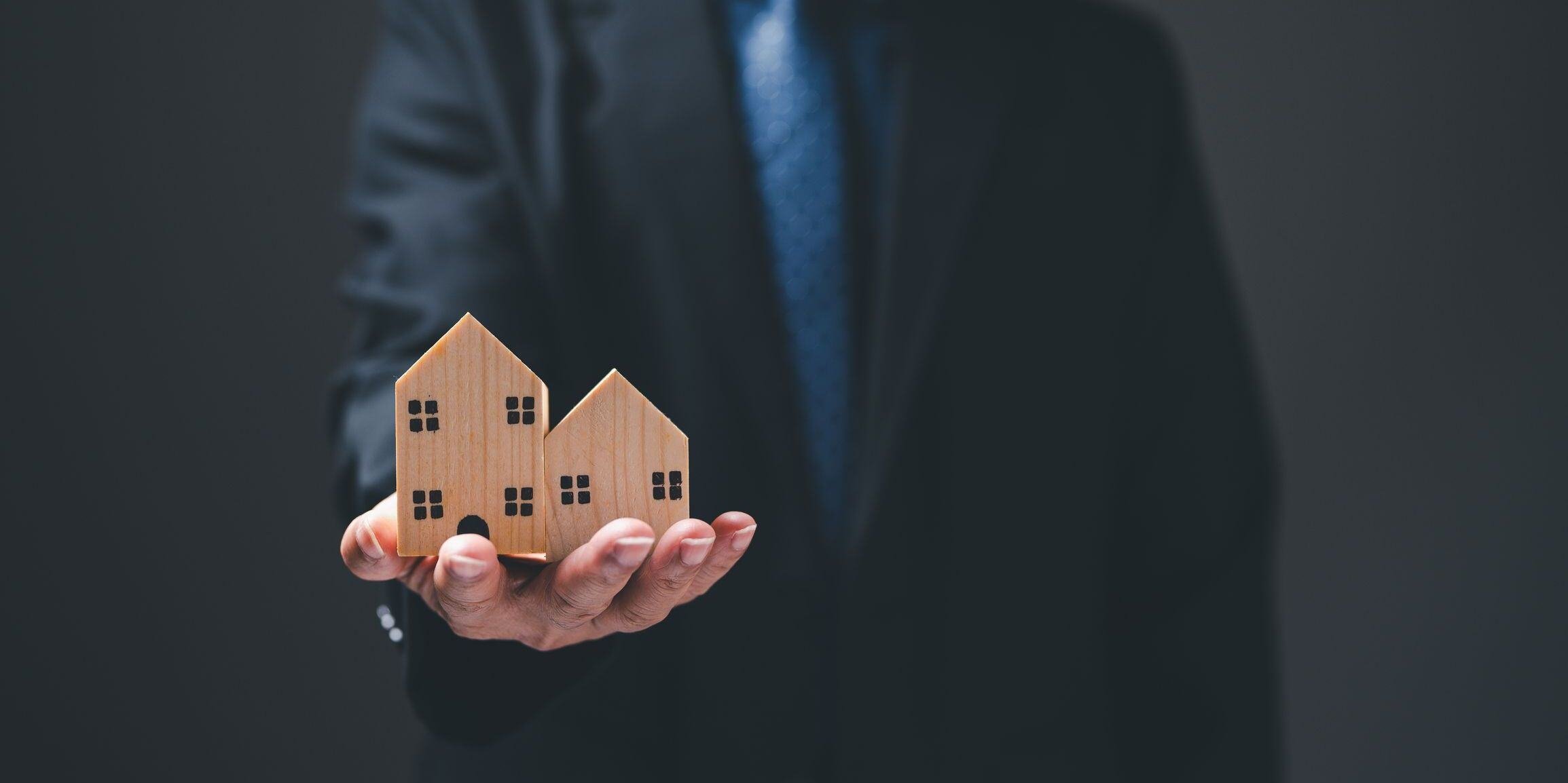 Man holding two houses 