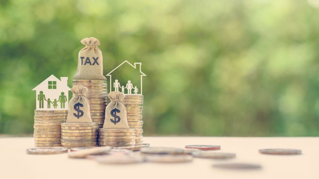 Coins and bag with dollar signs on them and the word Tax on a sign