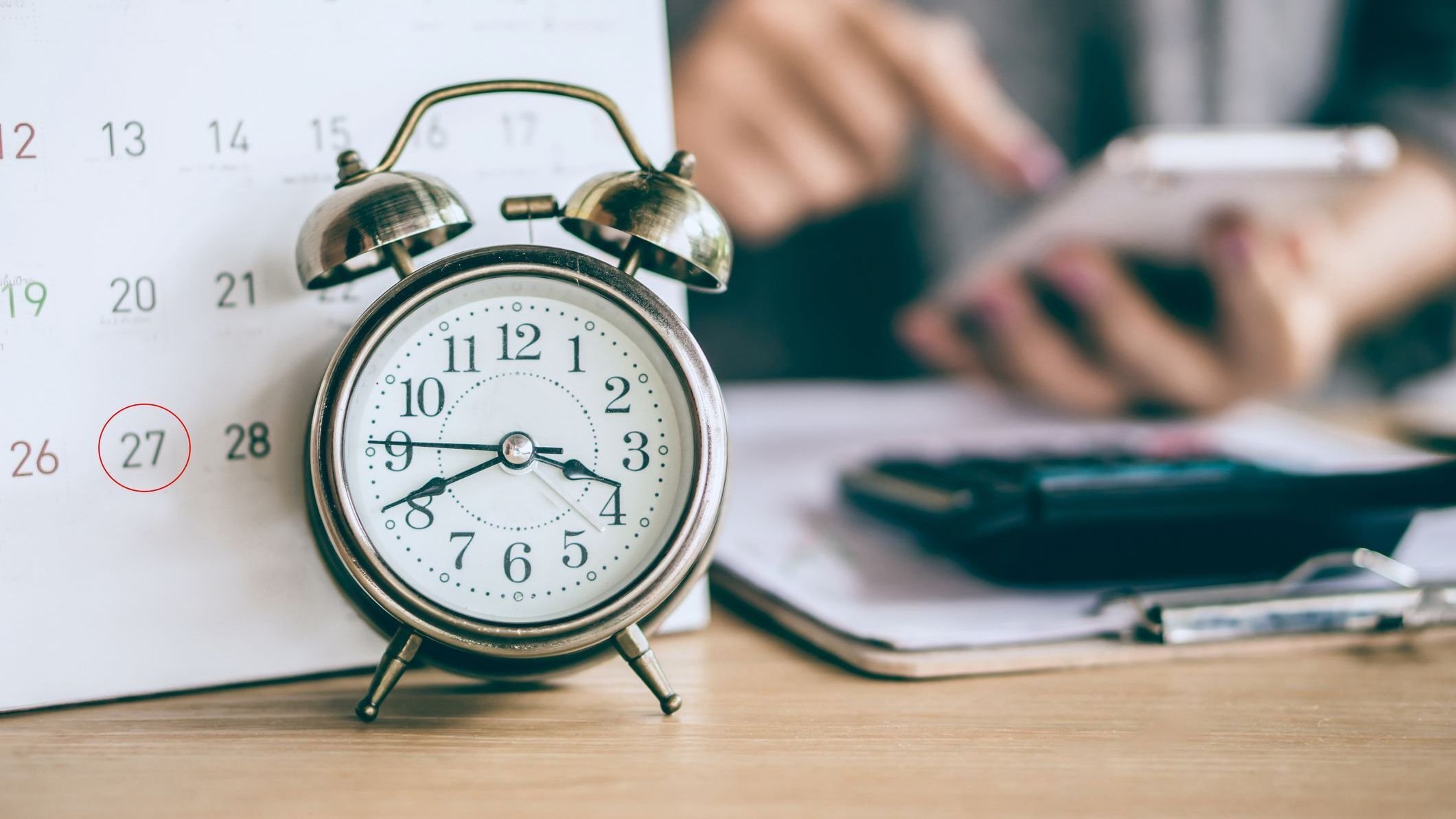 Due date calendar and alarm clock with blur business woman hand calculating 