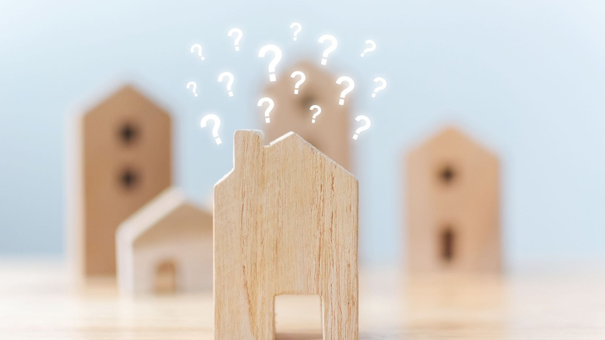 Selective focus wooden houses with question mark on table.
