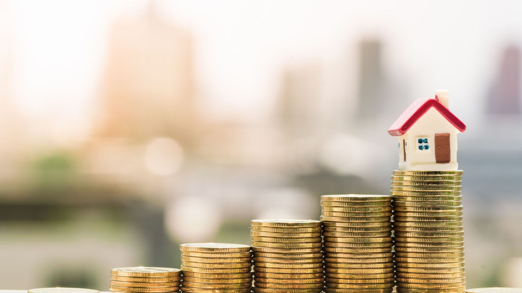 Stack coins growing with house sitting on top.