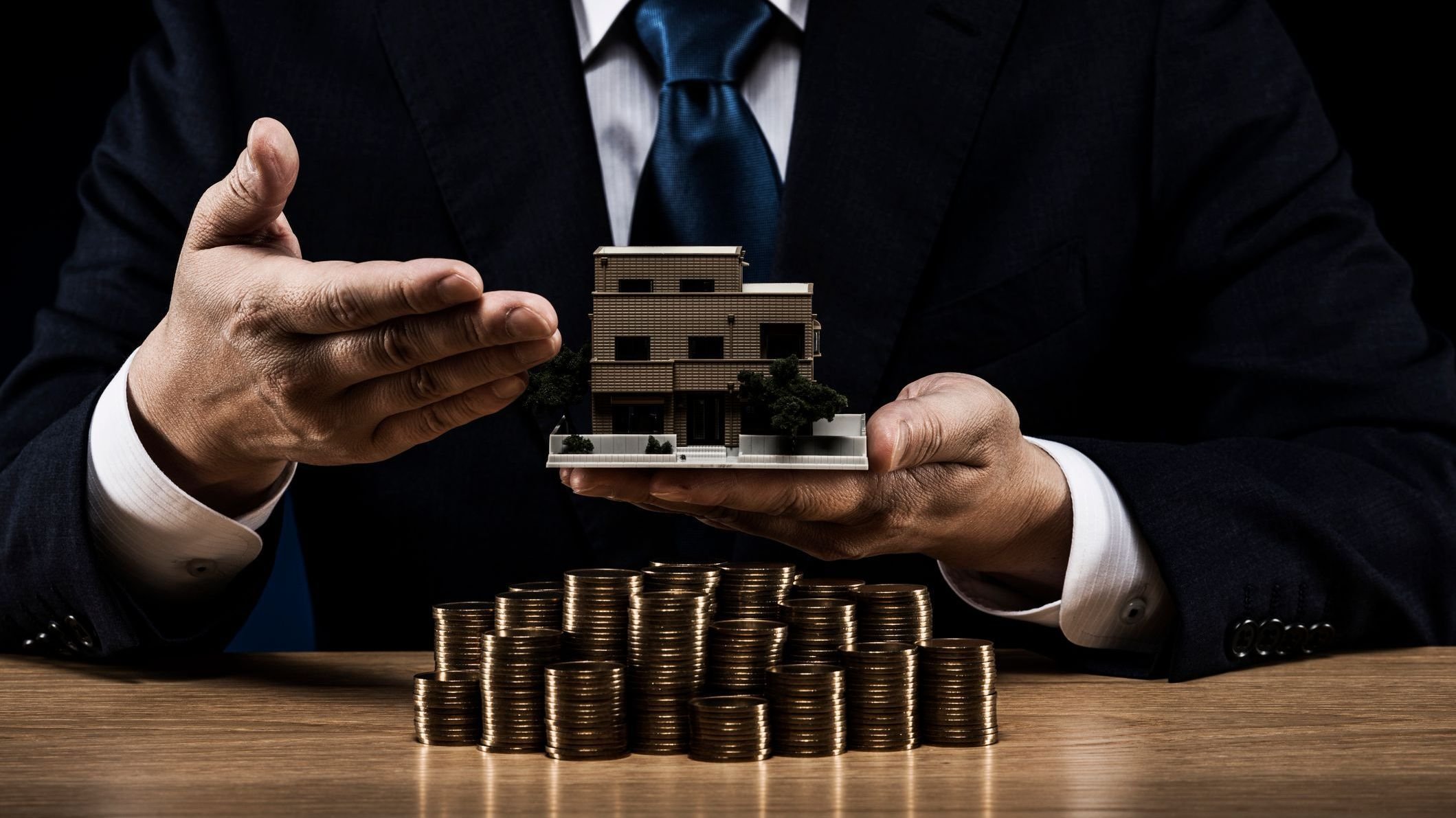 Businessman and pile of coins and house model.