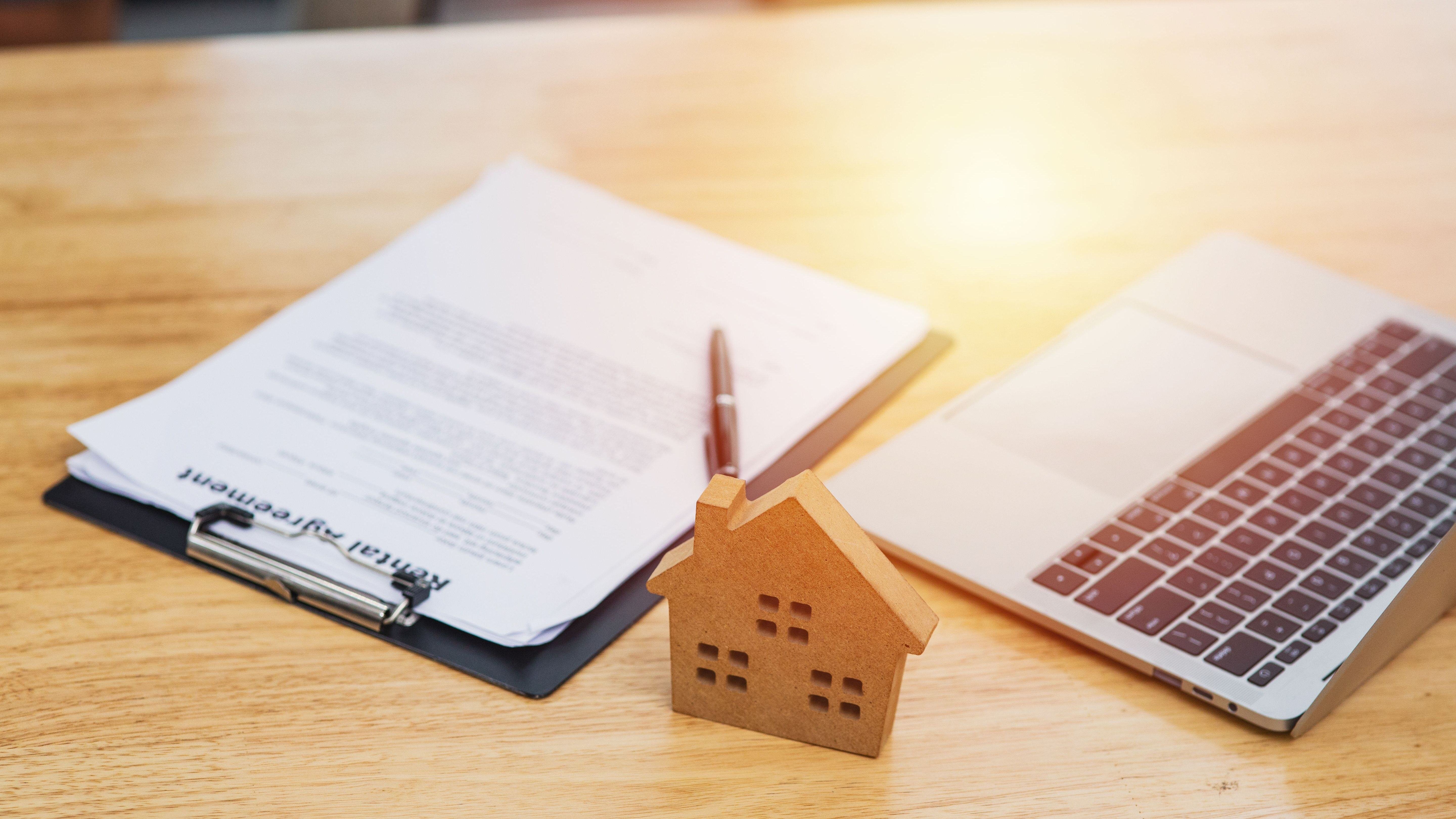 Home model put near Lease or Rental agreement document and laptop with copy space