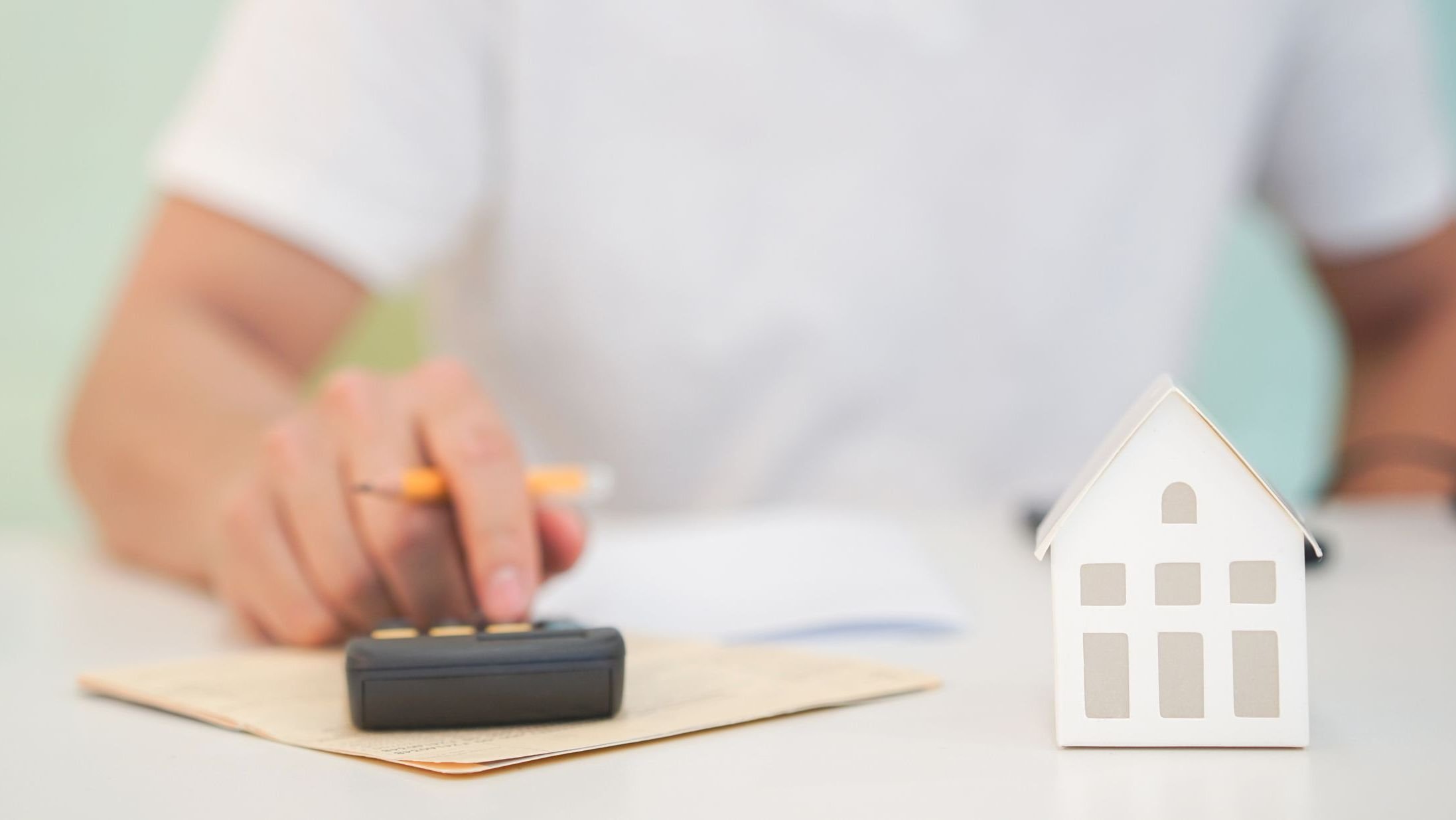 Close up house's model with young man hand counting on calculator.