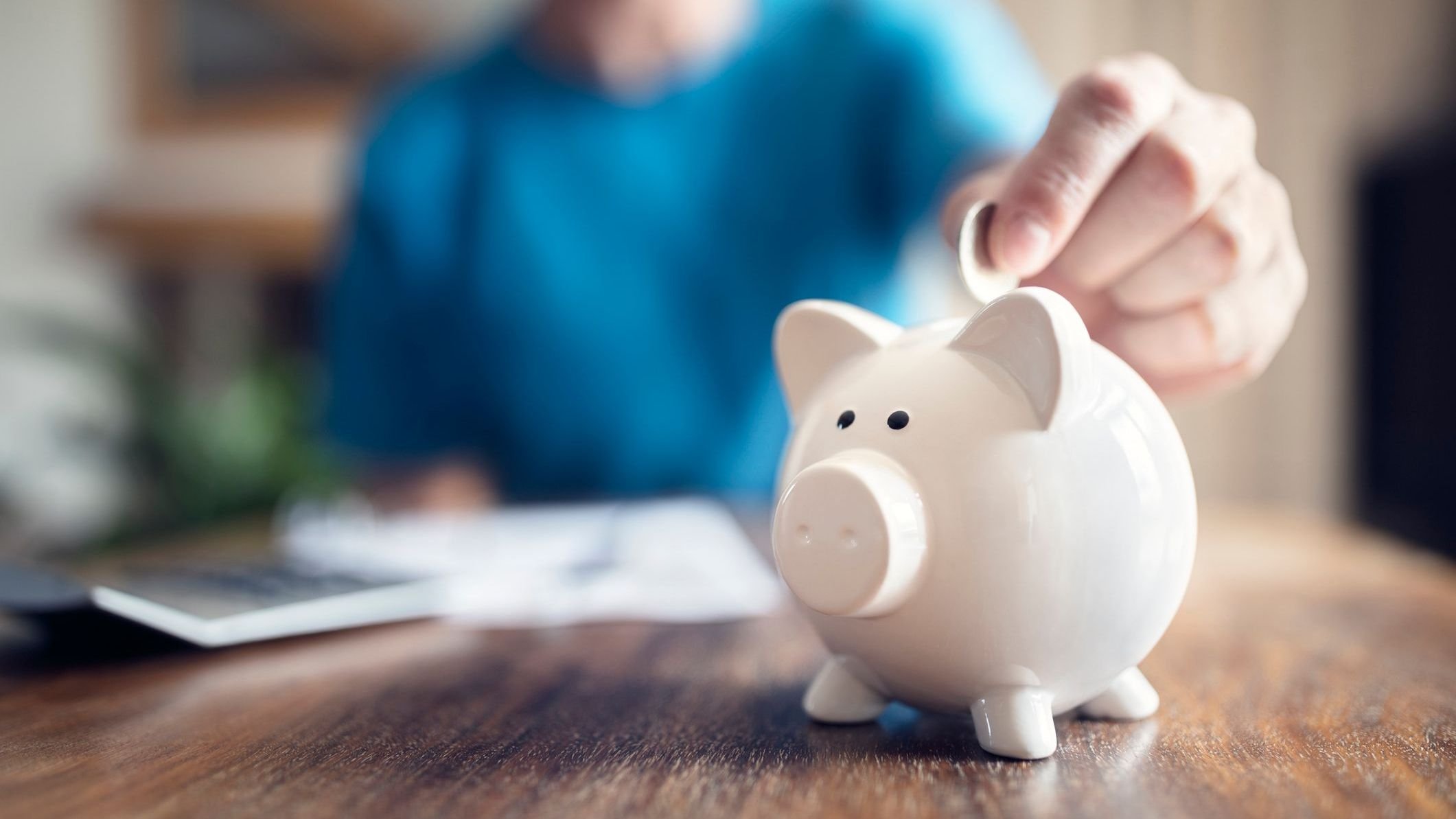 person putting coin in piggy bank.