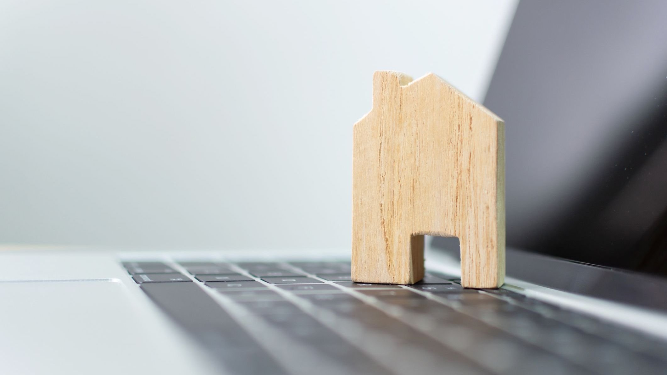 Small wooden house sitting on lap top. 