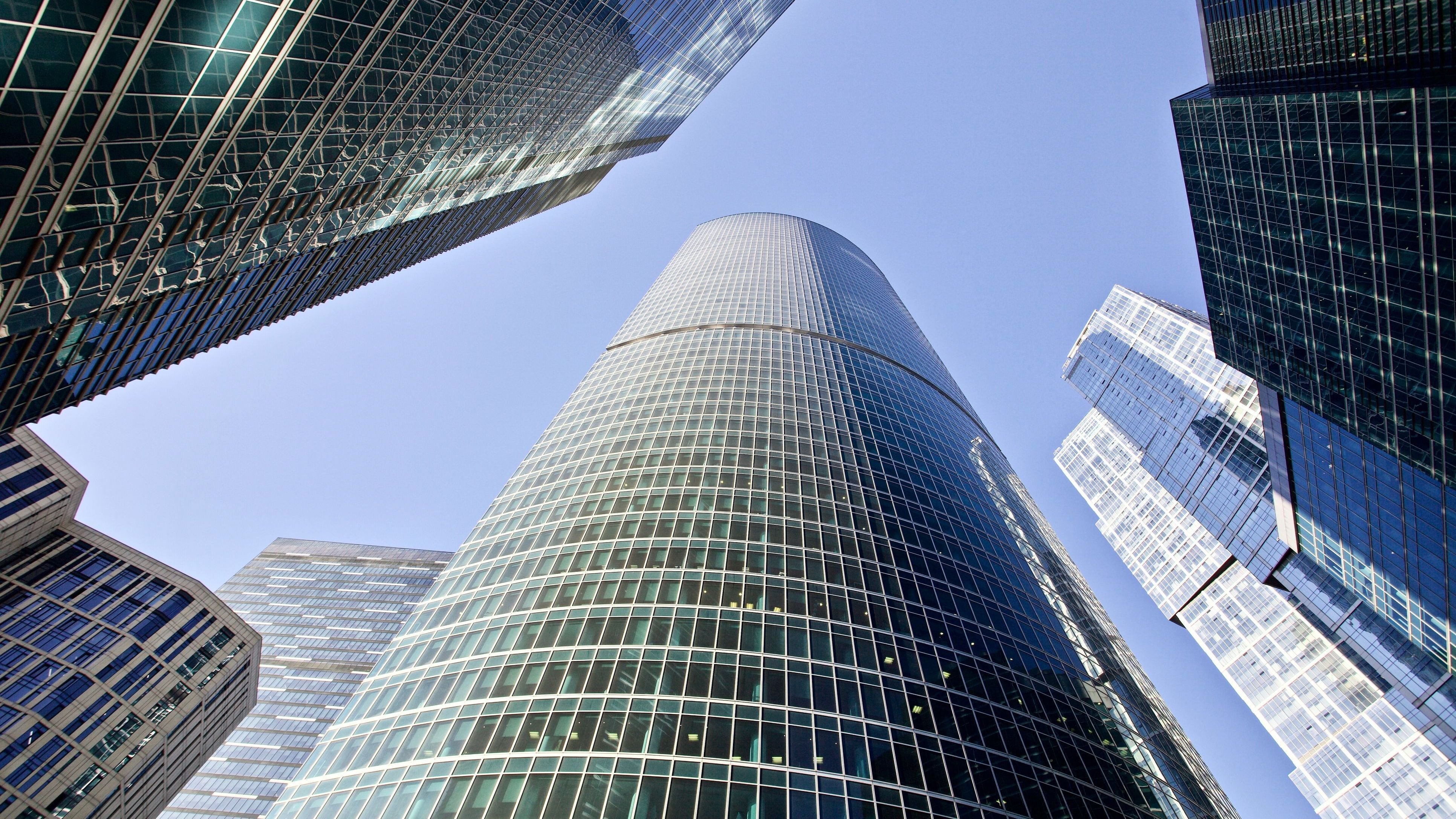 Bottom-up view of modern office buildings on bright clear blue sky.