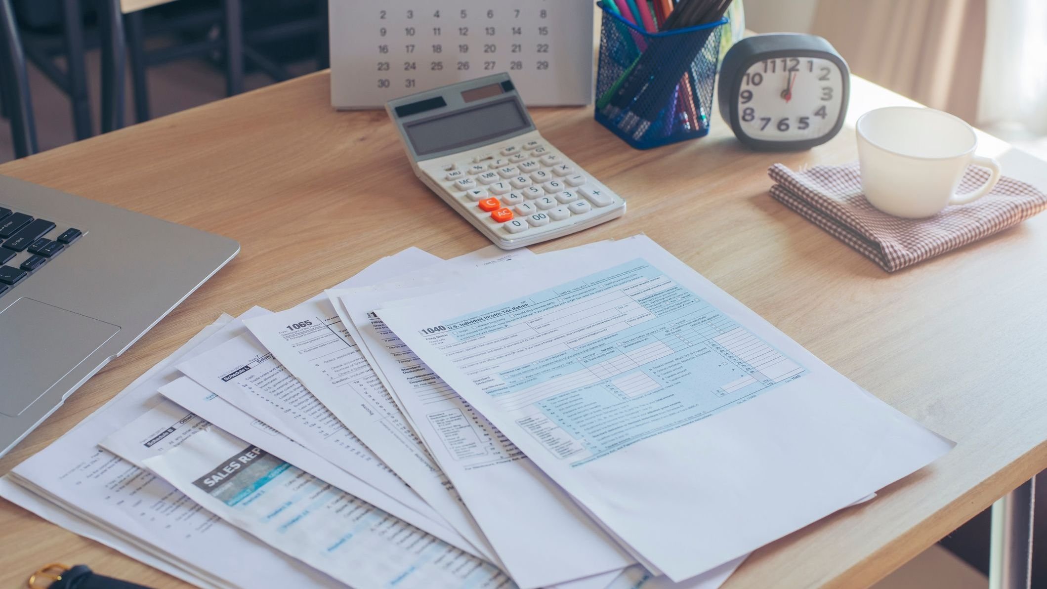 Stack of papers and a calculator sitting on desk.