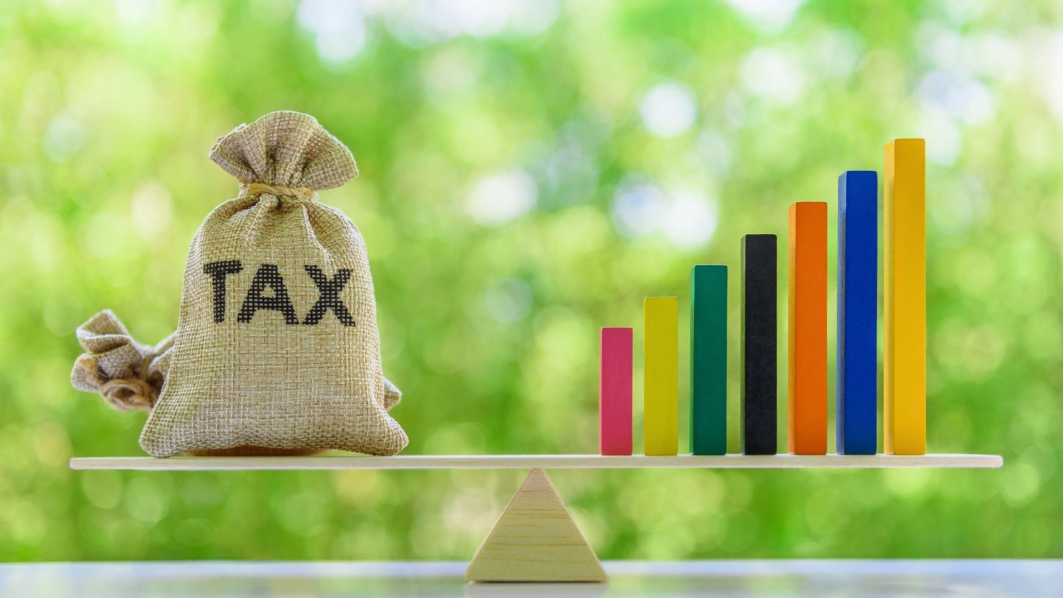 Tax bags, rising bar graph on a basic balance scale.