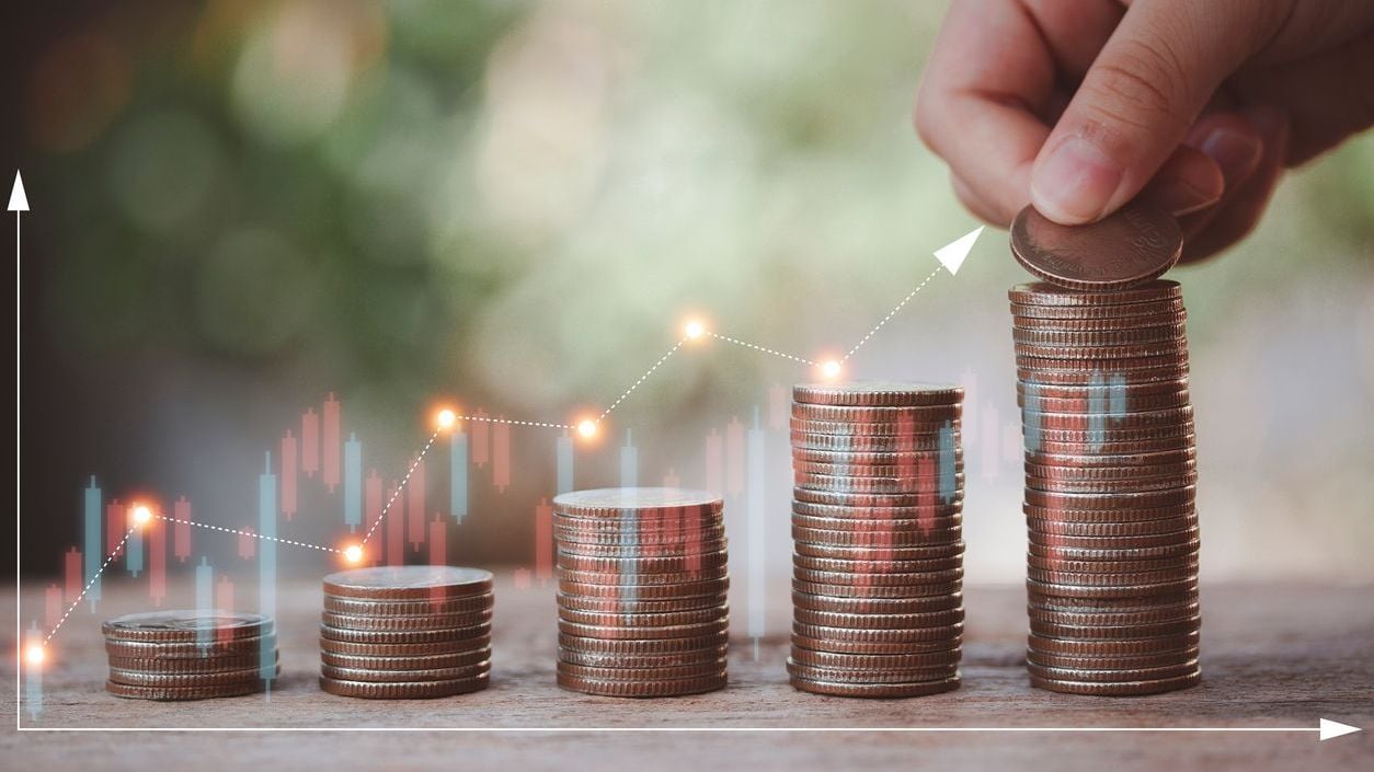 Stacking coins with hand of child putting money on top.