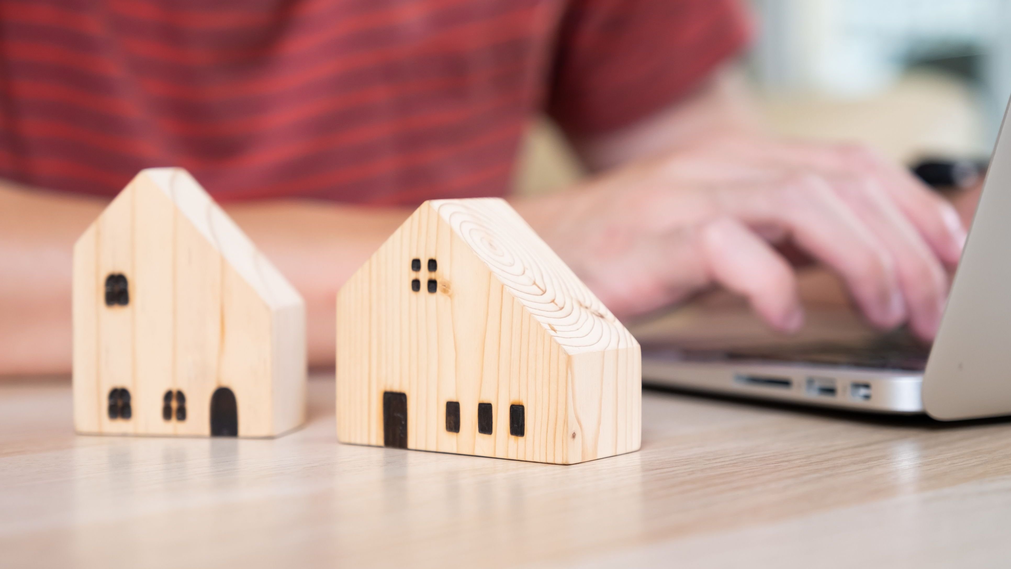 Selective focus at wooden house model with calculator and paper note on wood table.