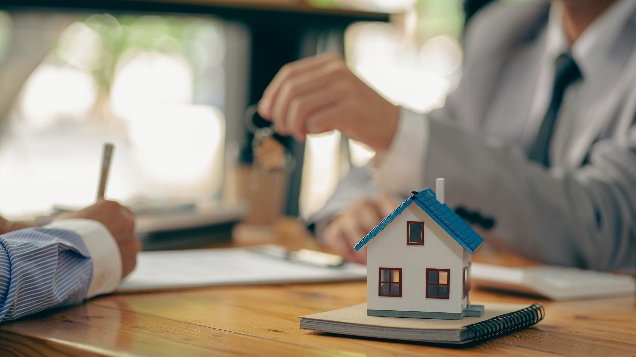 Sales representatives hand out the house keys to customers after signing a contract to buy a house or rent a new home on the table.