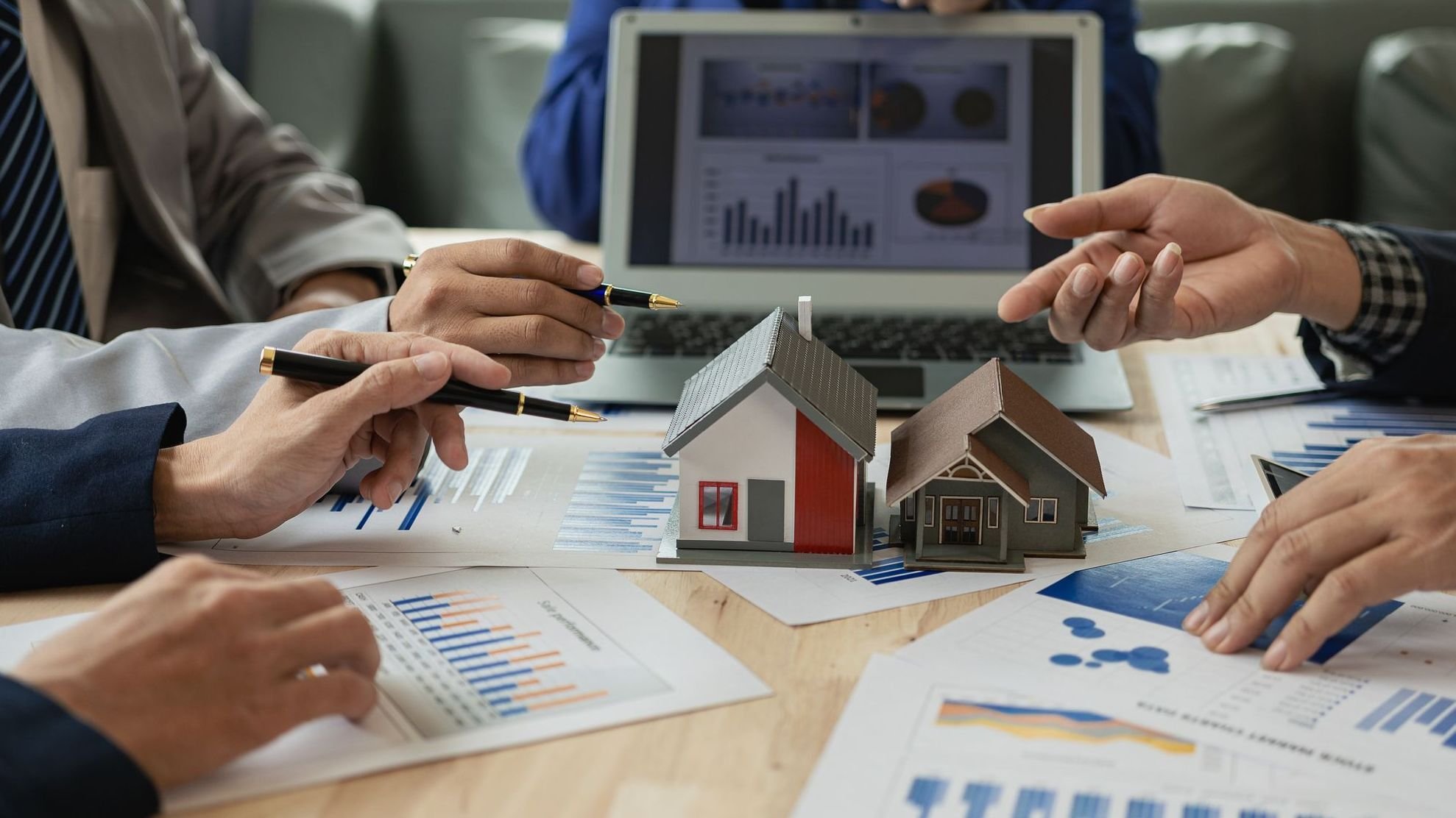 Businessman Holding Graph Over The Increasing House Miniature, Real estate investment,investment mortgage finance and home loan business, growth and money. 