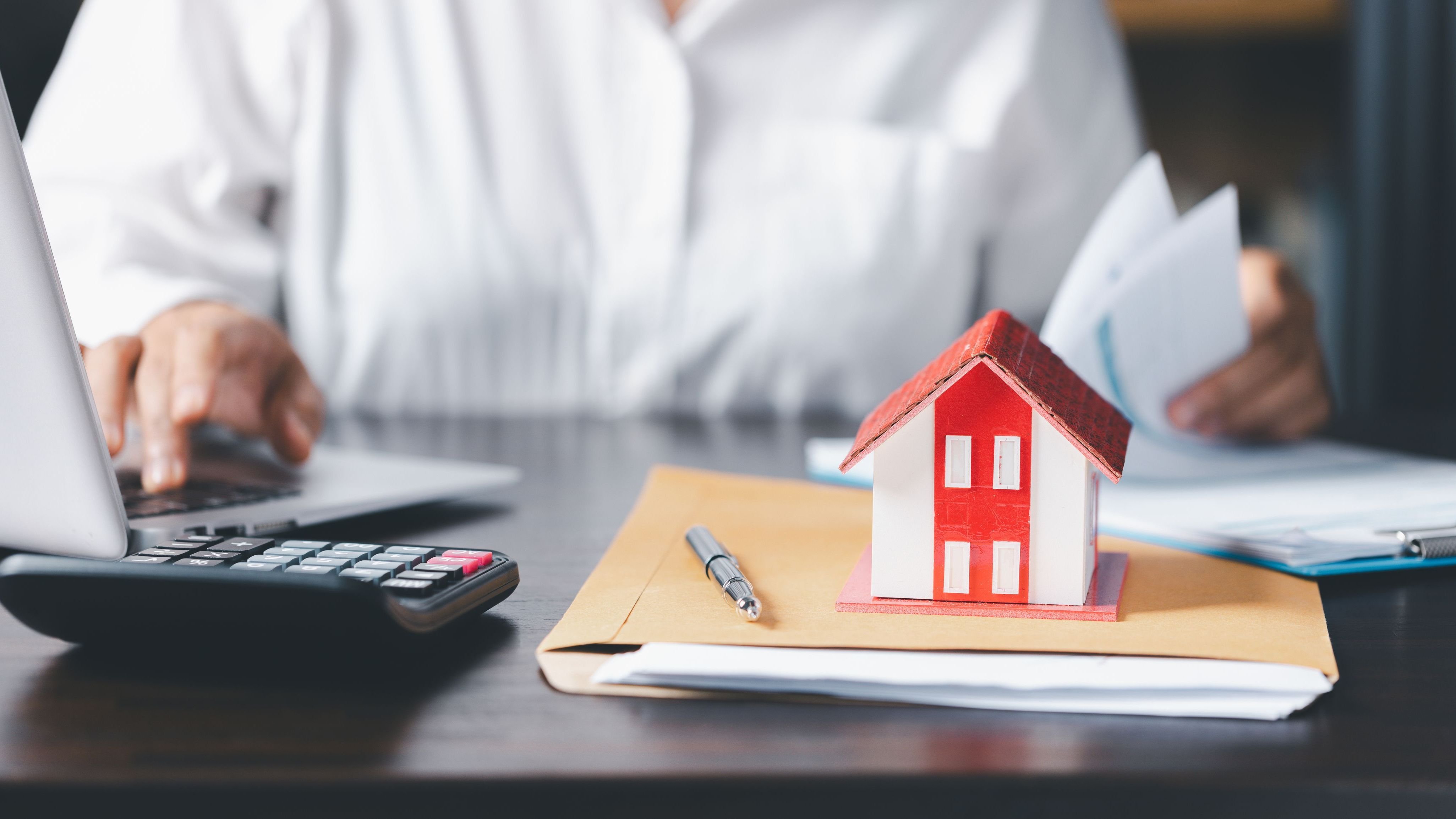 House model with real estate agent and customer discussing real estate background.