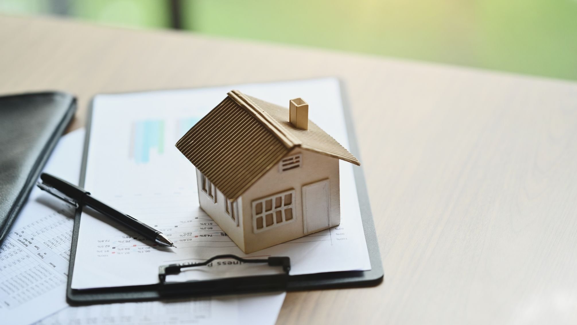 House model and documents on wooden table.