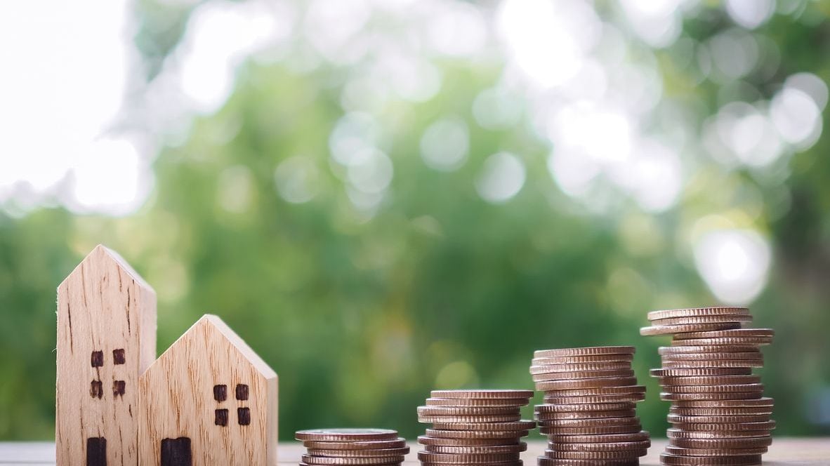 Miniature house and stack of coins.