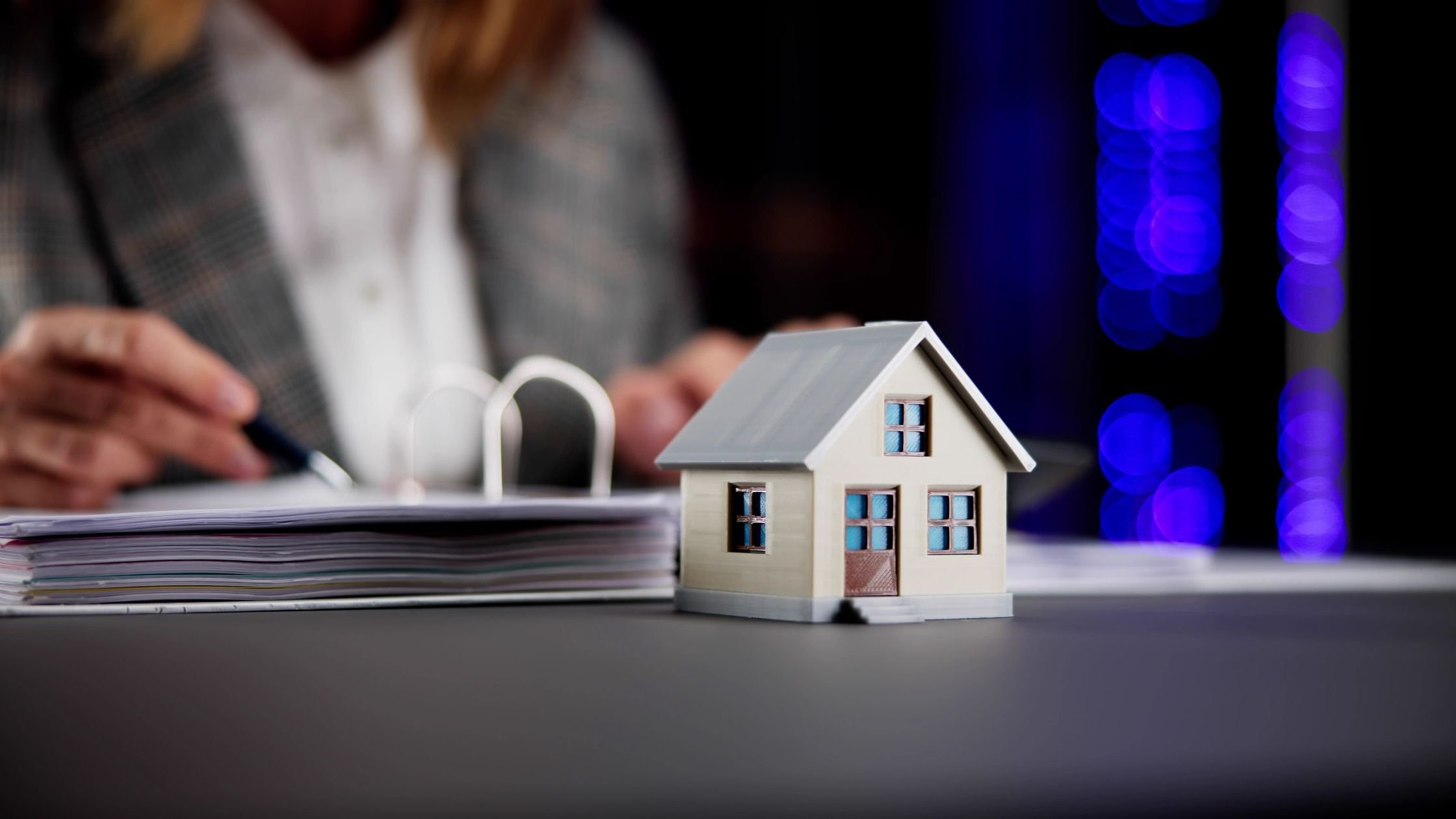 Little wooden house in front of person looking at papers.