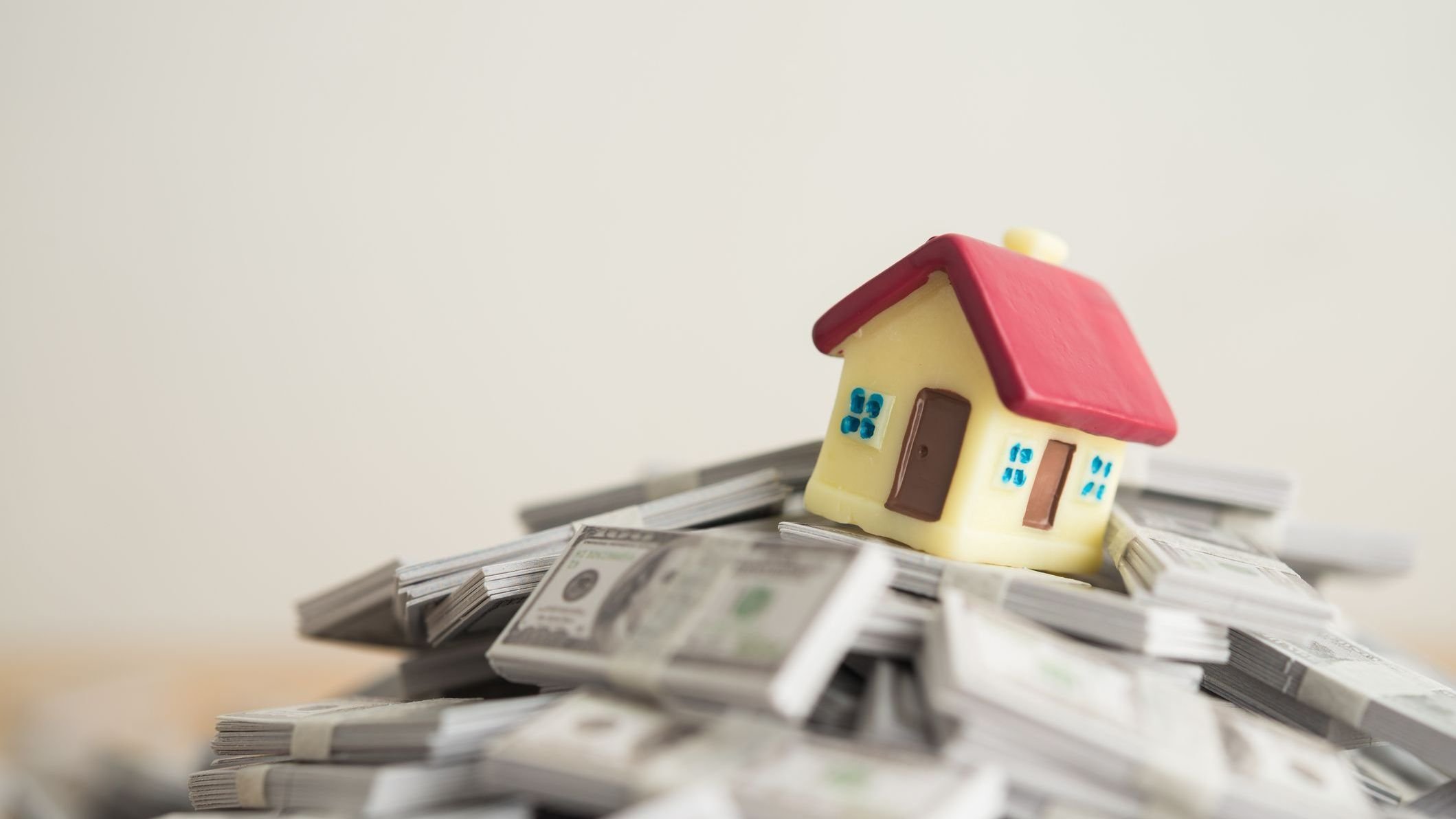 House on stack US dollar banknotes with white wall background.