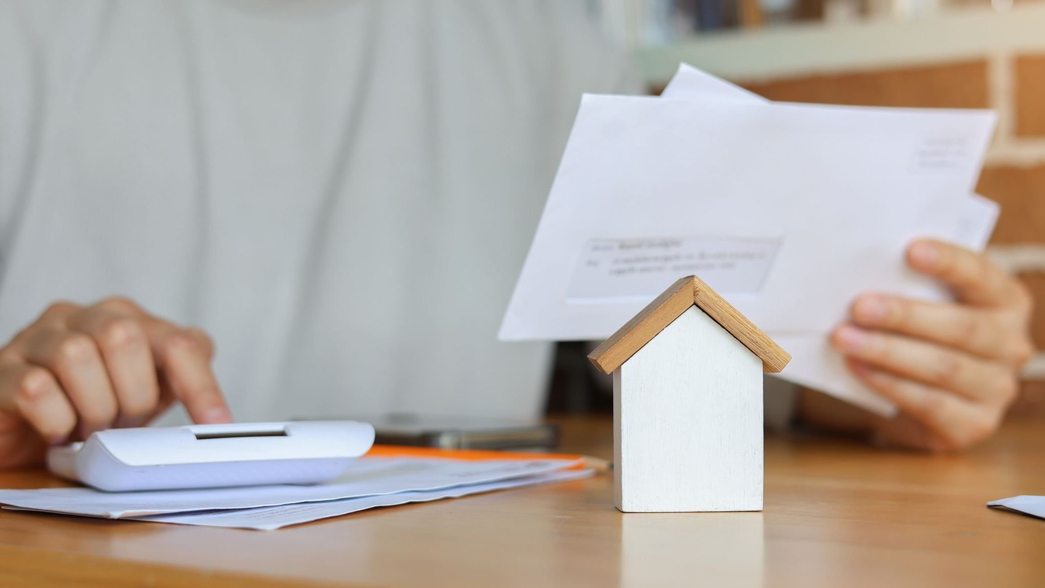 Close up house's model with young man hand use calculator.