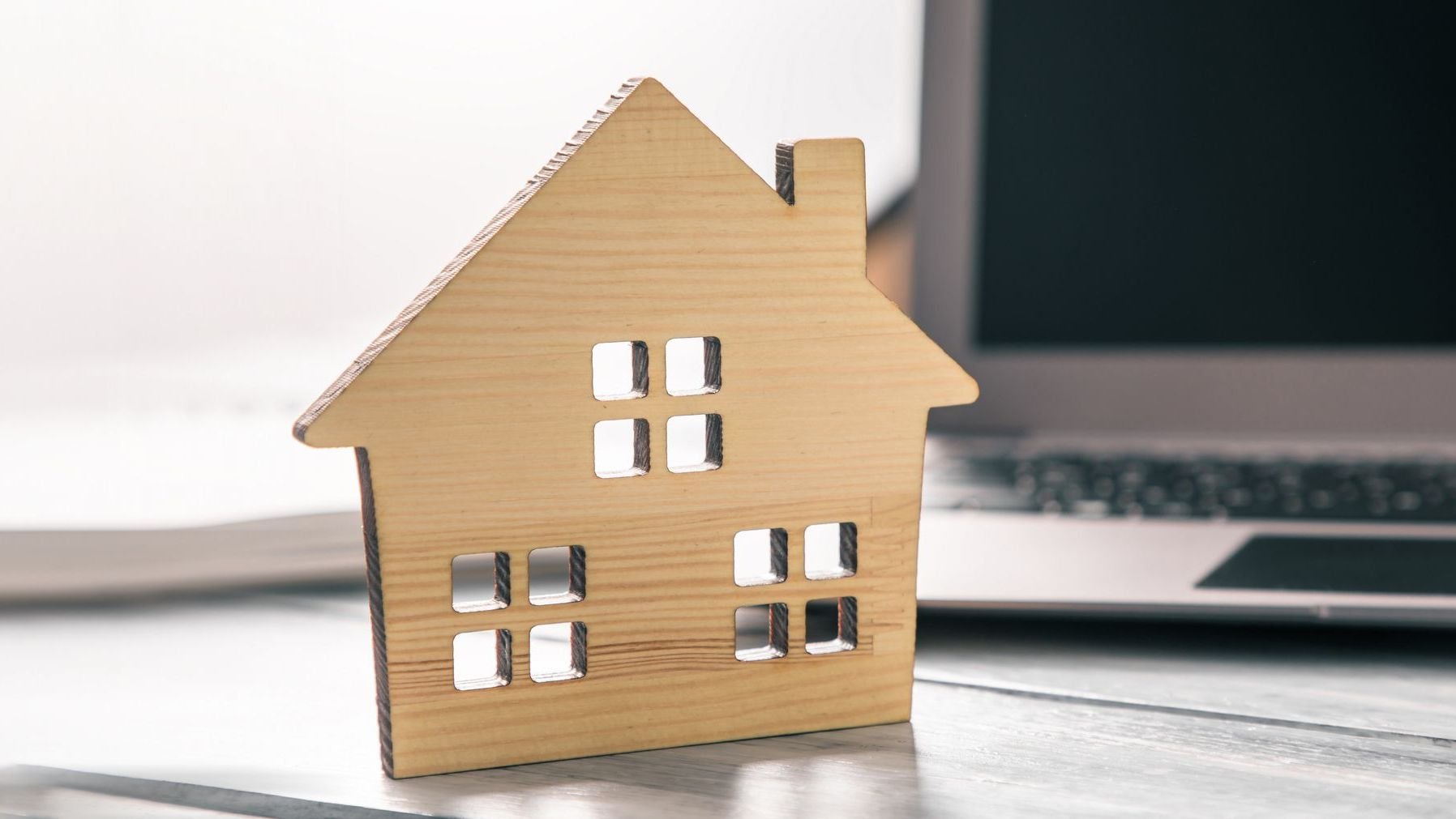 Wooden house model on computer laptop.