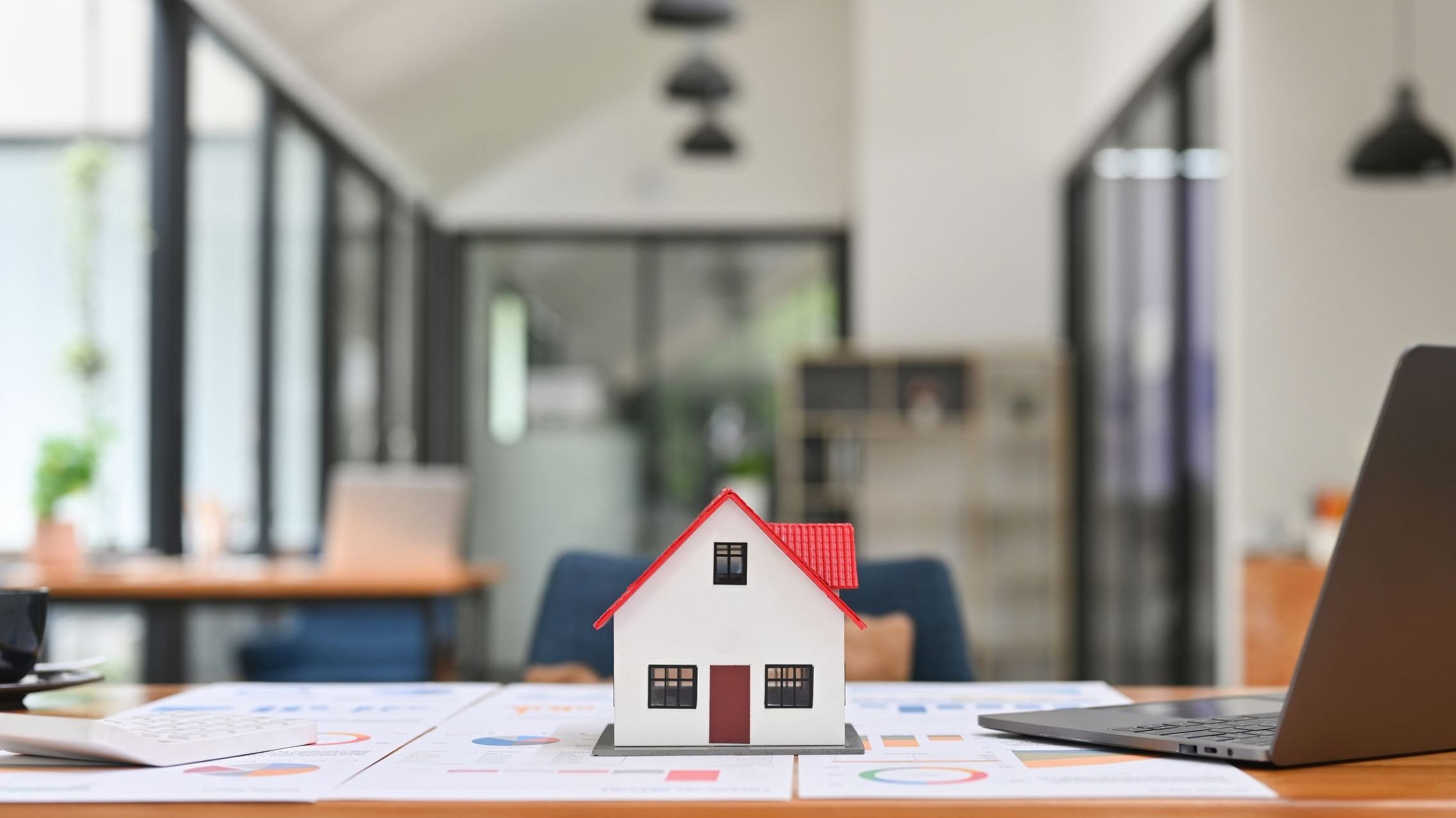 Close up of mockup house and key placed on home brokers desk.