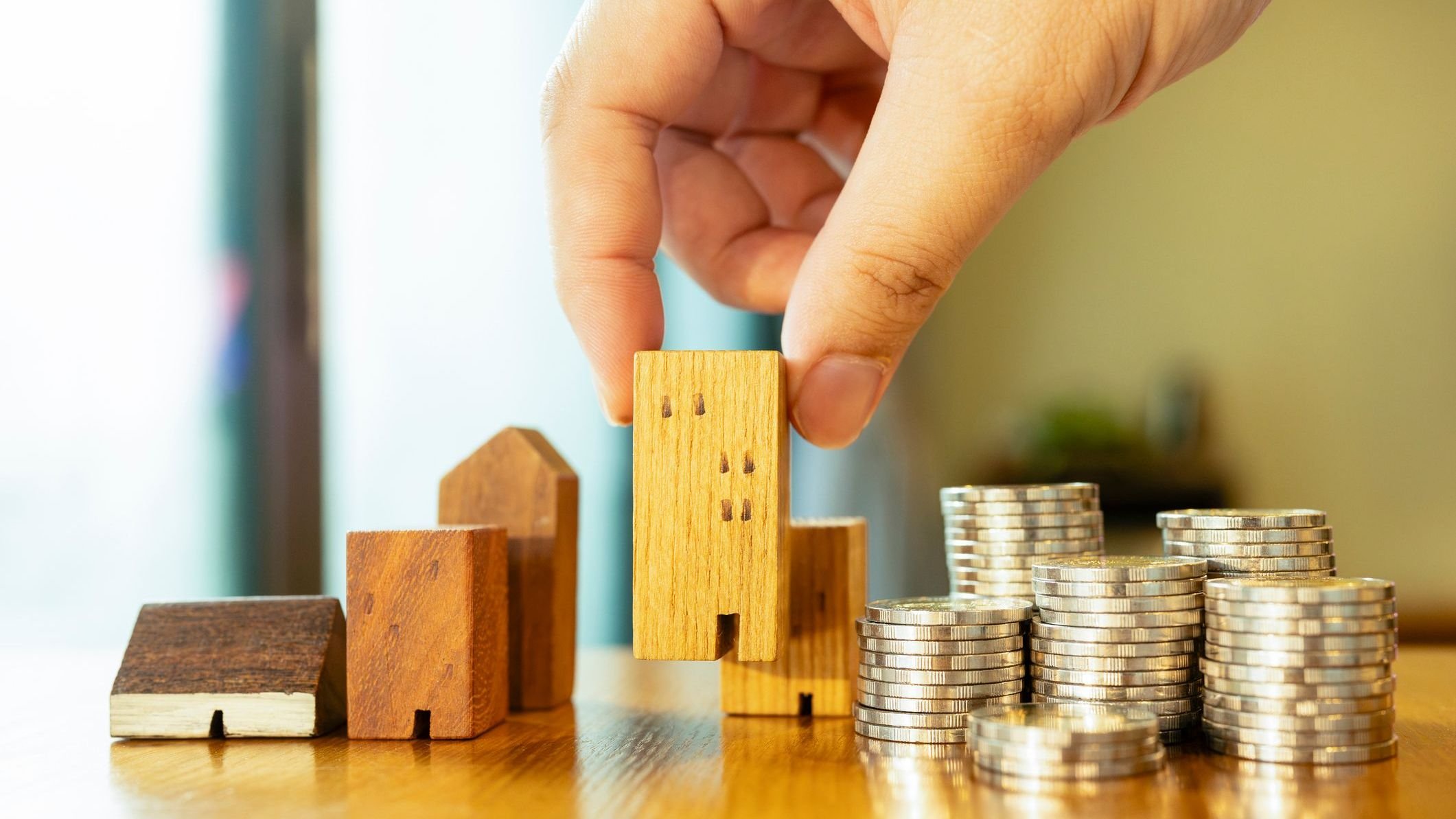 Wood house and row of coin money on wood table.