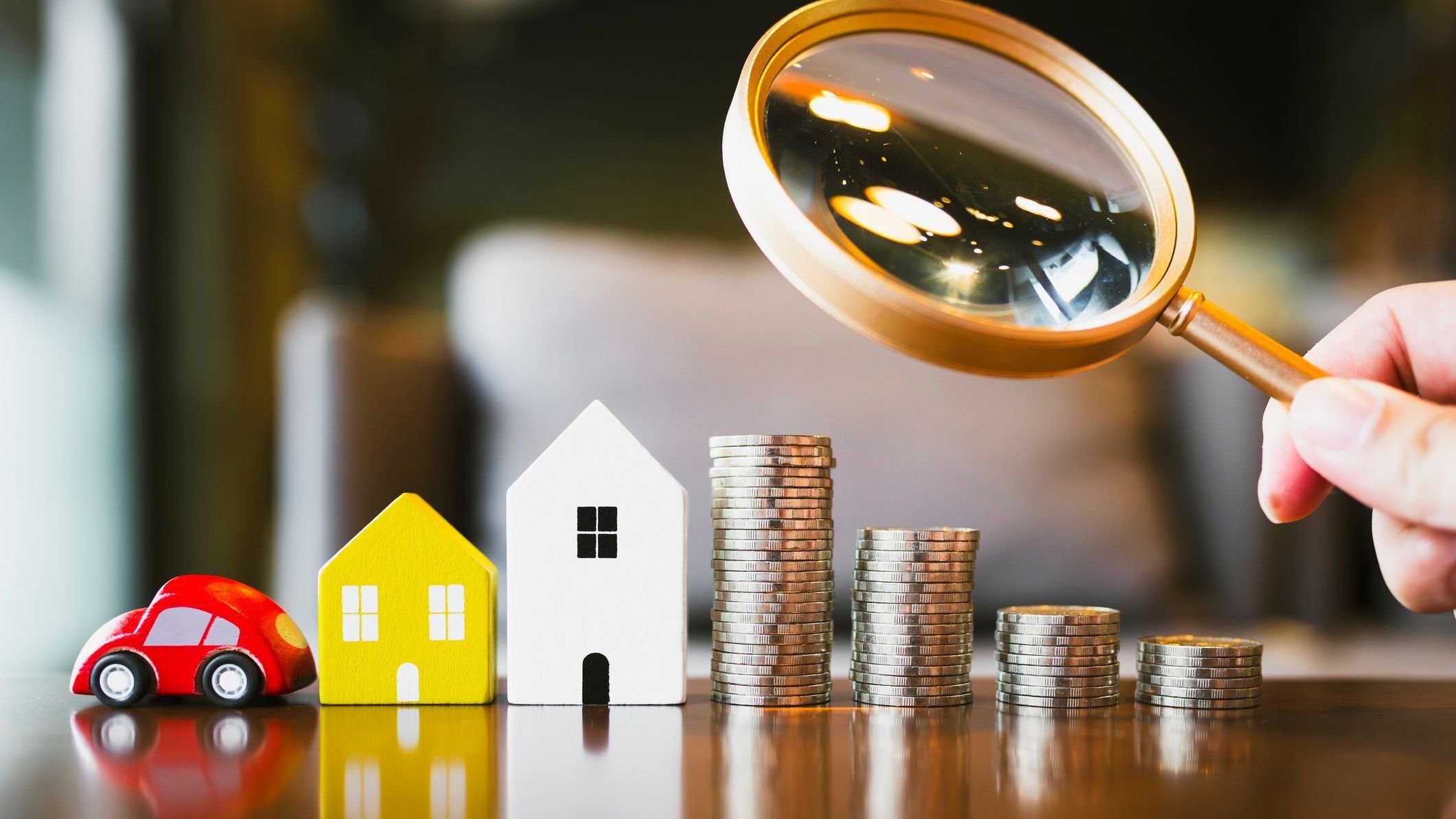 House, car and coins on wooden table.