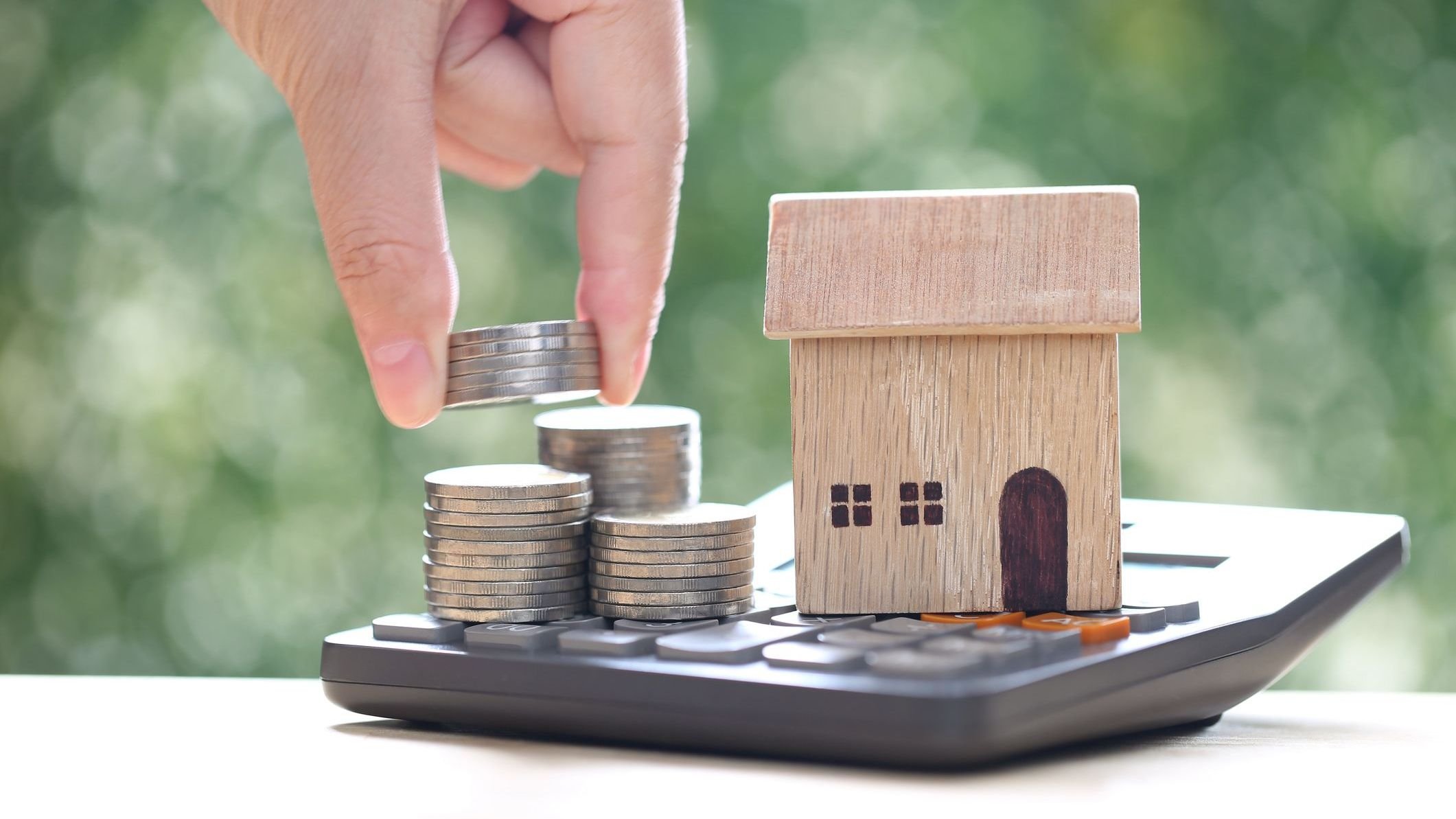 Calculating interest payments, Model house on calculator and stack of coins money on natural green background,Business investment and real estate concept 