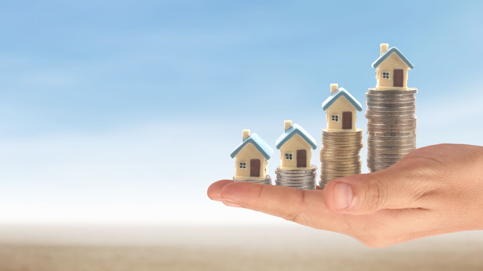 Hands and stock coins and model house.