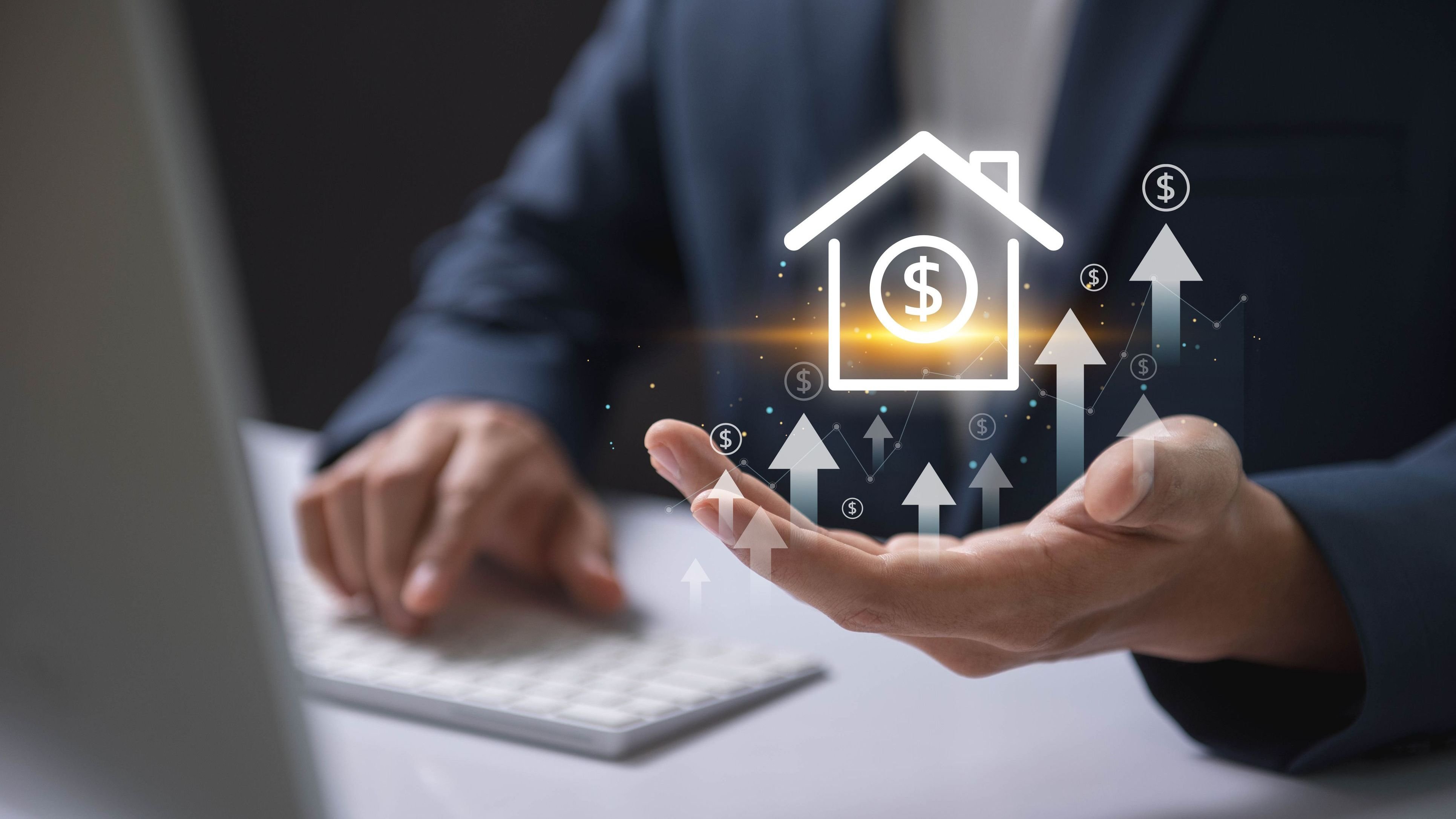 Businessman holding a virtual house icon with dollar signs and upward arrows.