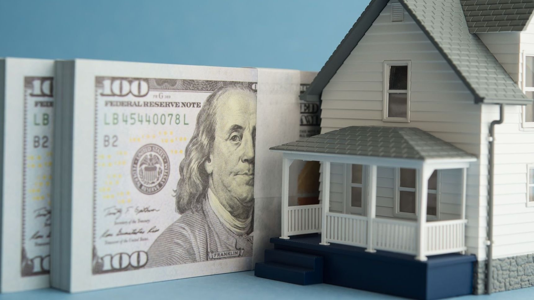 House and US dollar banknotes on blue background. 