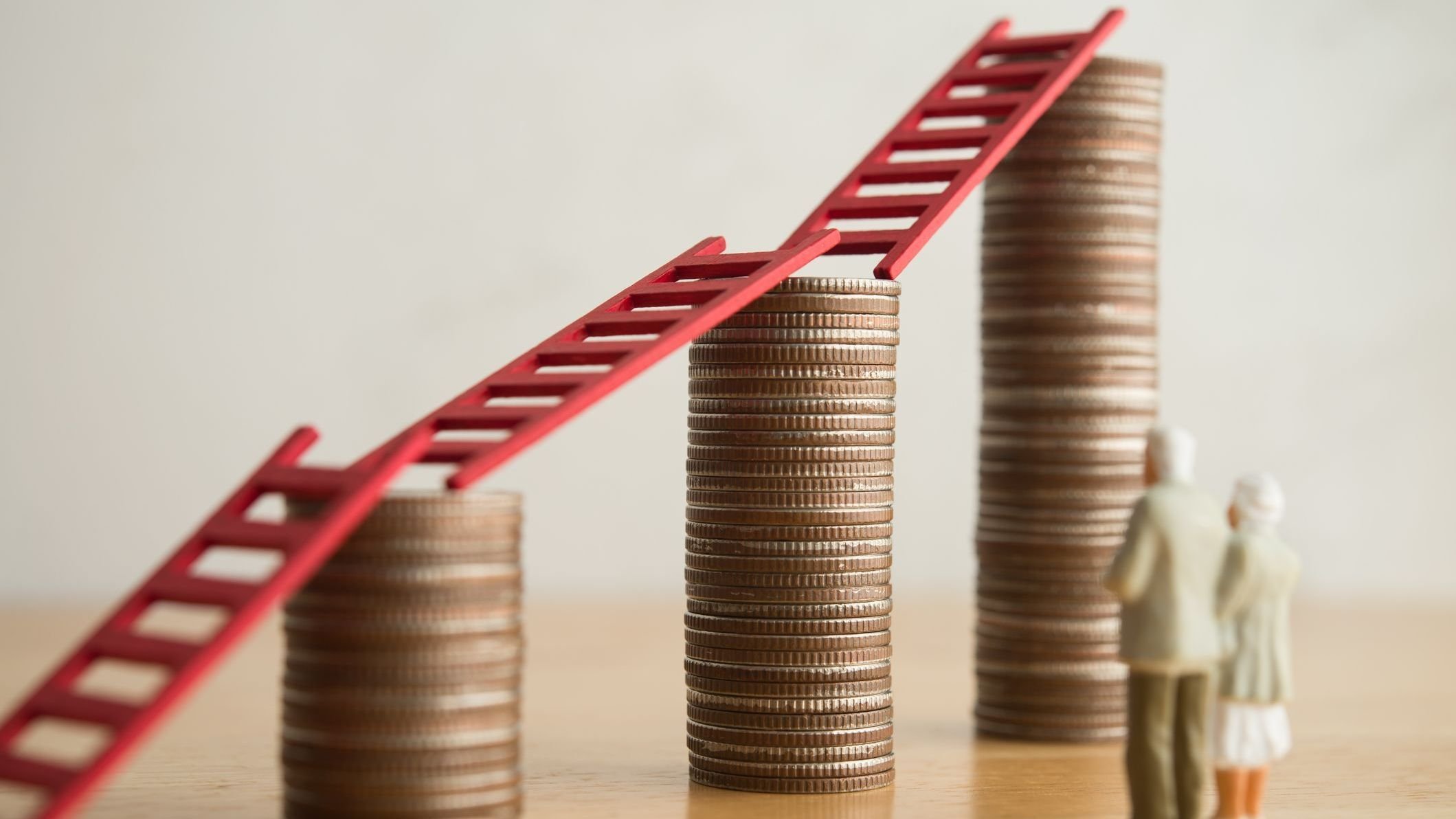 senior couple looking at growth stack coins graph chart with red ladder.