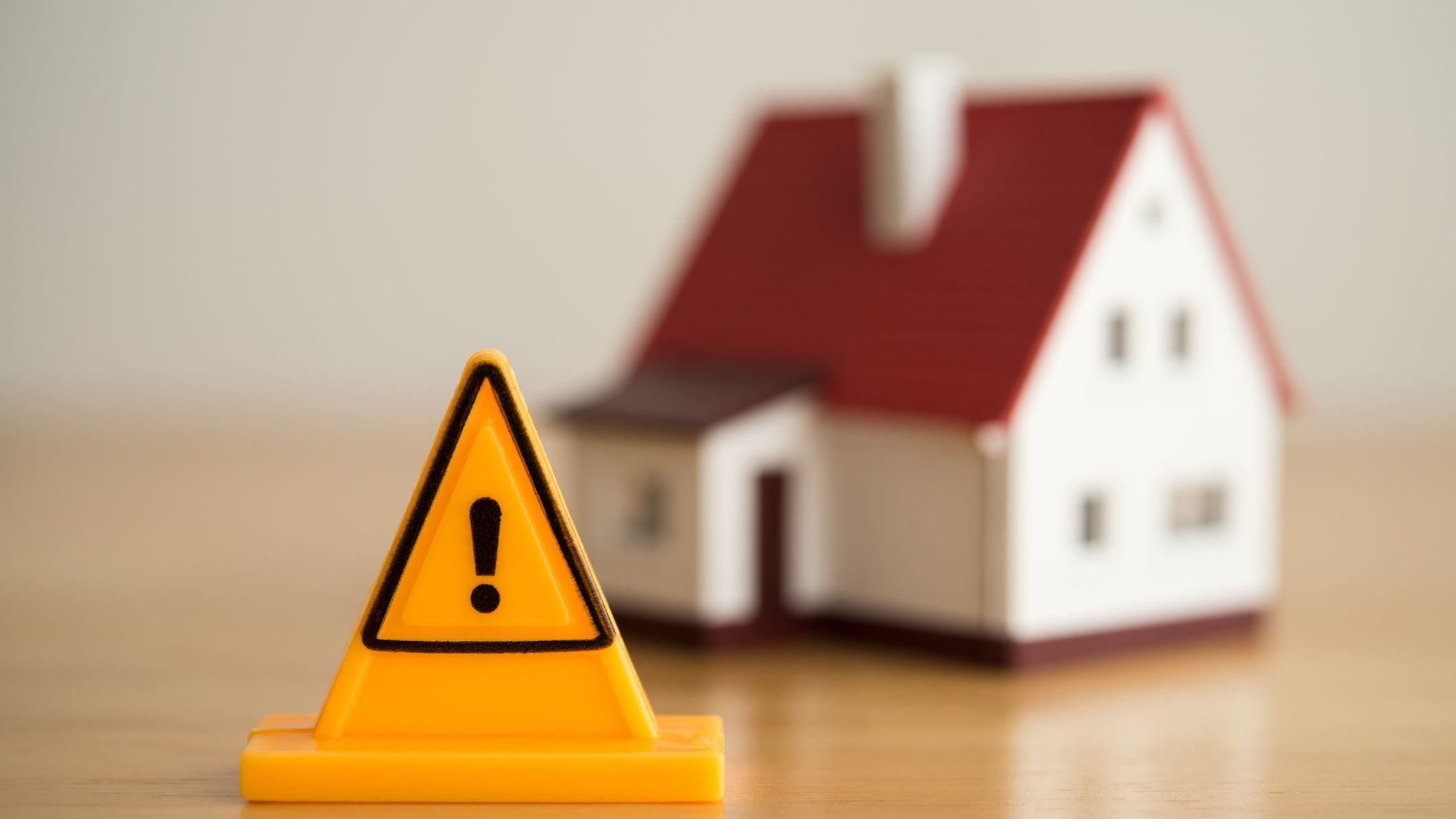 Emergency notification warning sign label with model house background.