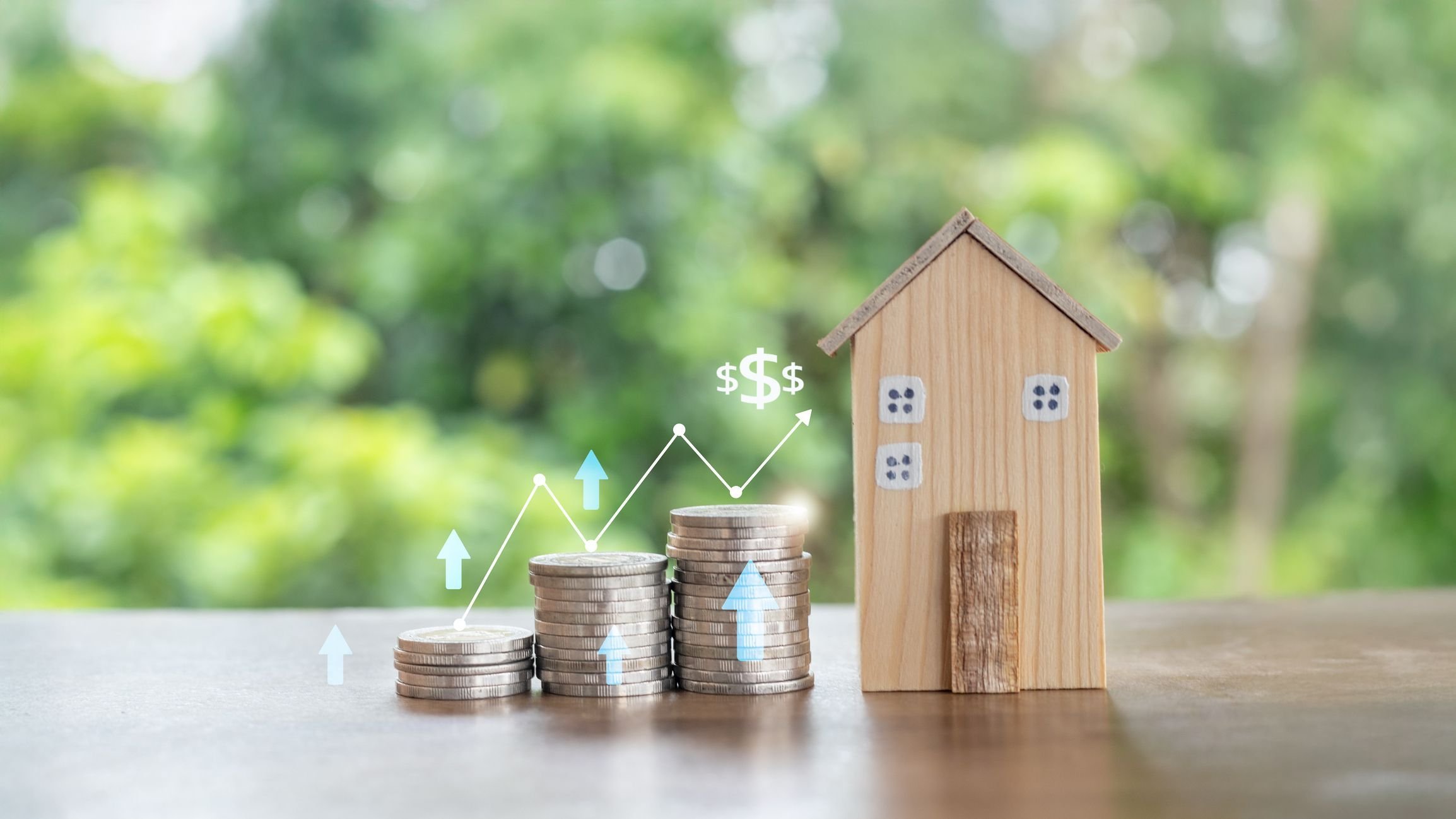 Stacks of coins with a growth chart and a wooden house model representing real estate investment.