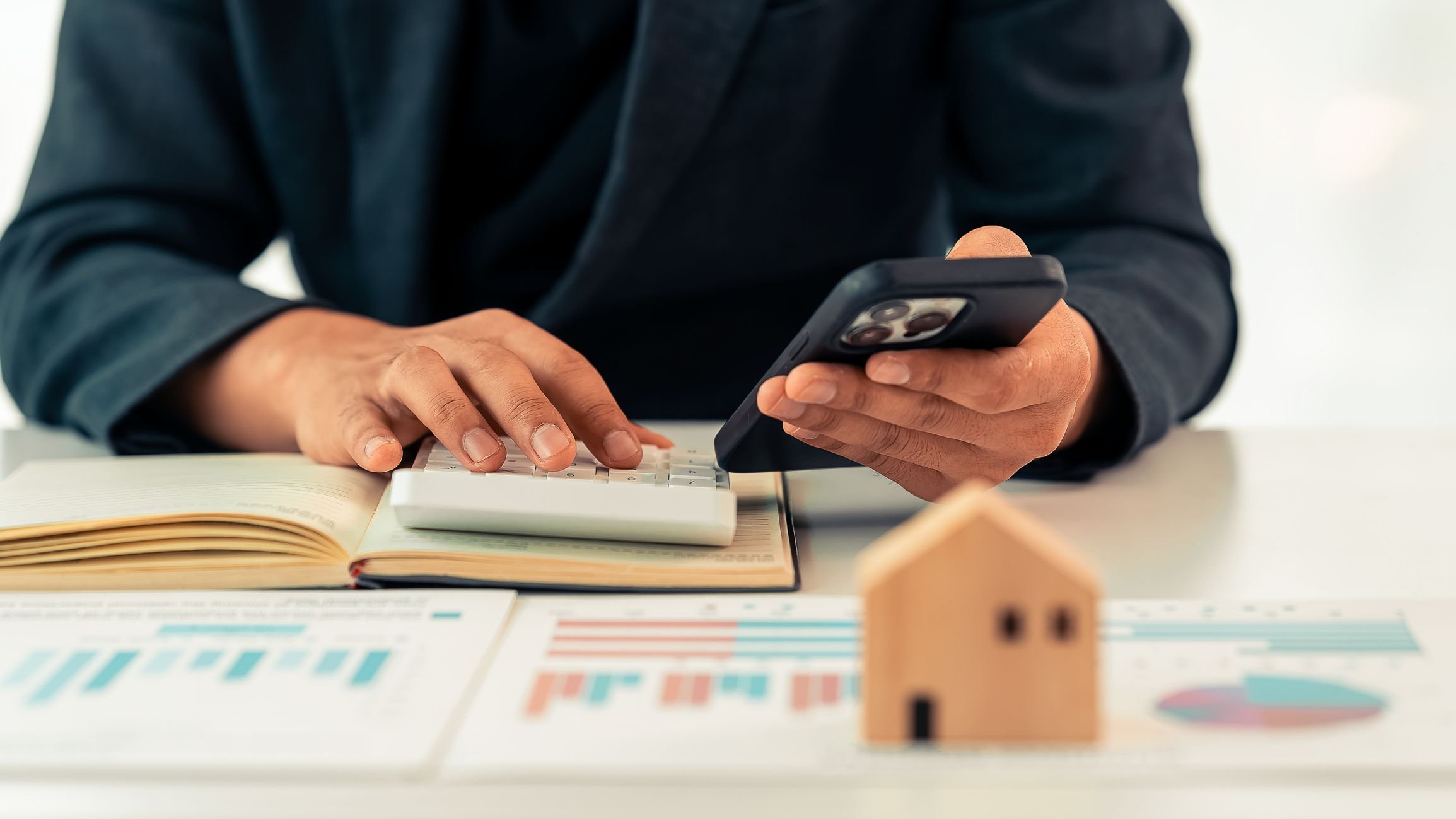 Real estate agent presenting home loan to client for signing contract with modern house model.