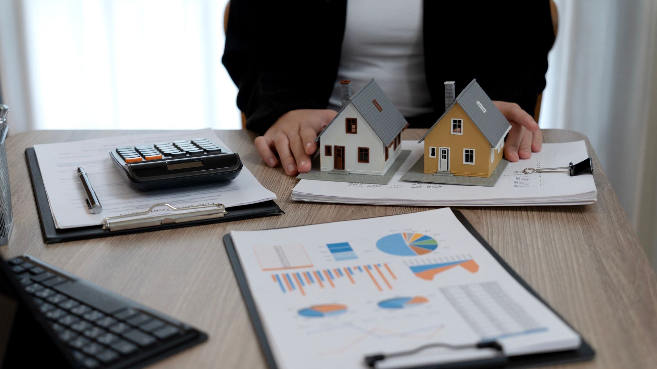 Real estate professional analyzes property models and financial reports for home purchase investment planning