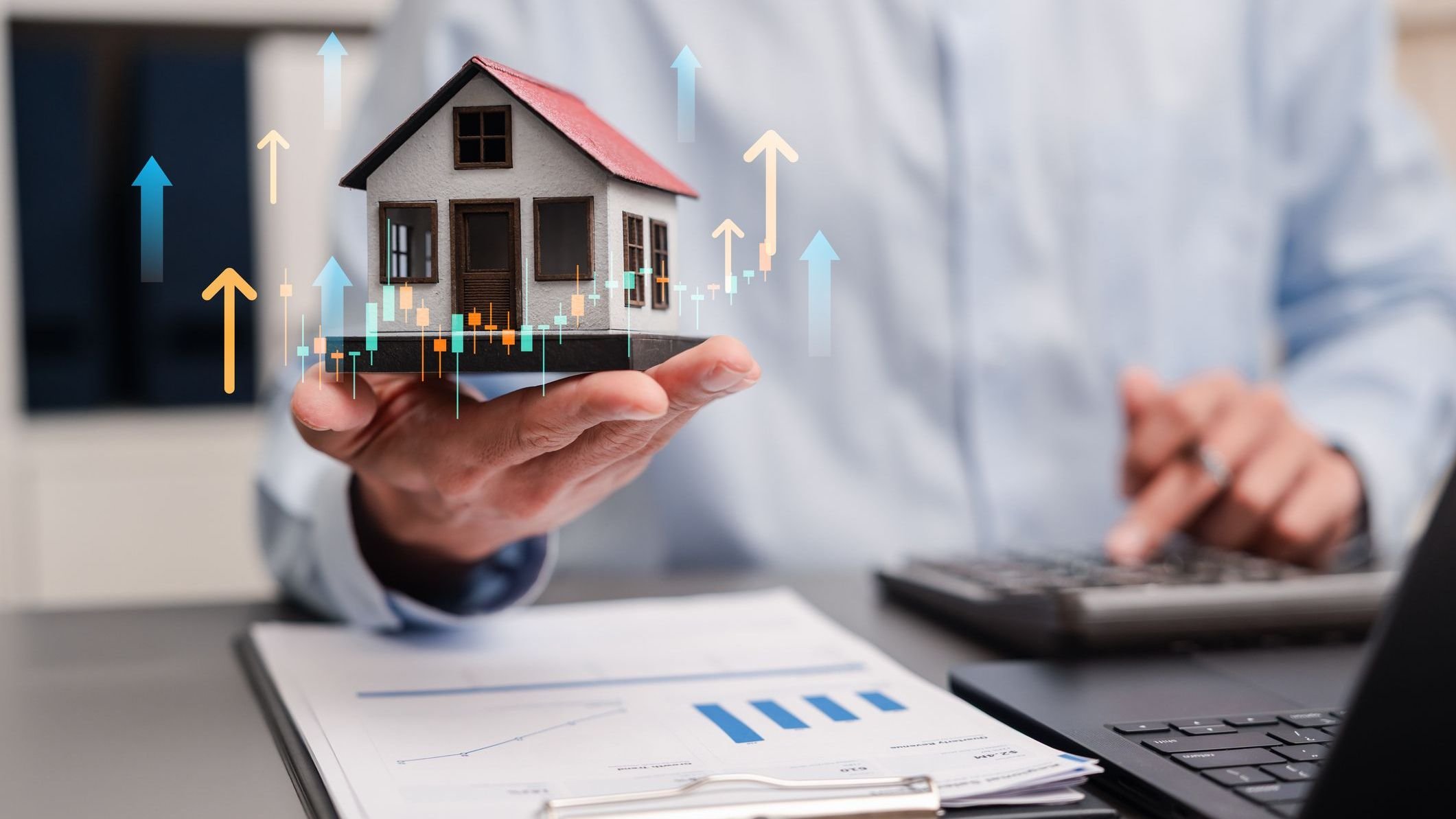 Real estate property investment and financial growth concept. Man holding model house with upward graphs and calculating mortgage.