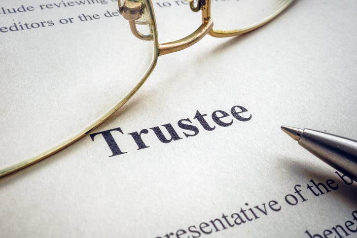 Image of the word Trustee on a sheet of paper with glasses right above it.