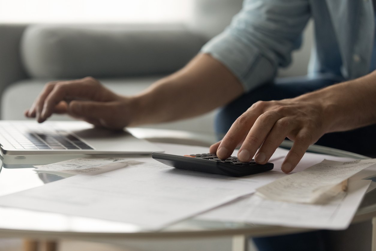 A picture of a hand typing into a calculator trying to calculate 1031 exchange expenses.