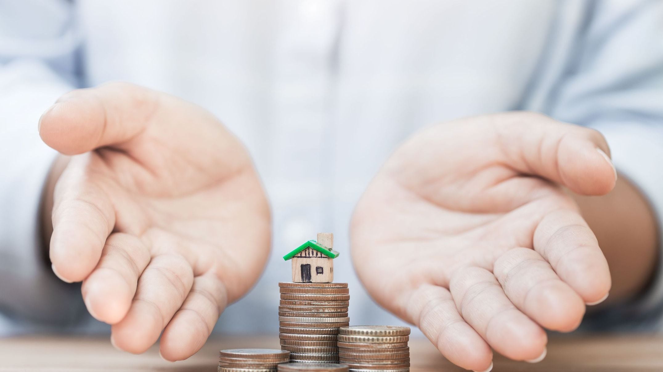 The hand of the person who is giving the house and the coin. The concept of loan for real estate, investment, buying a house. 