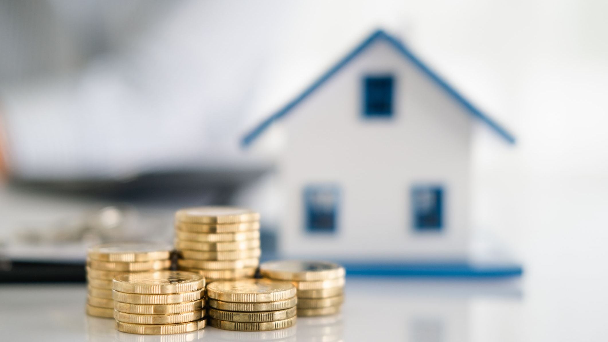 Coin stack with house model on table. Business growth background.