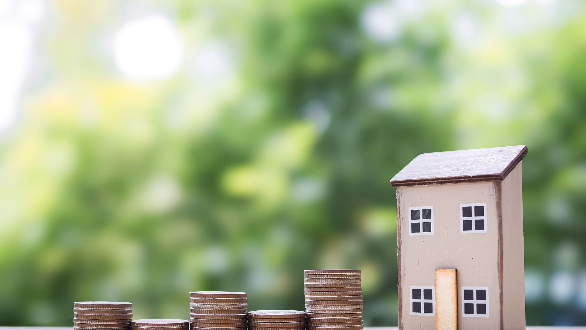 Miniature house and stack of coins.