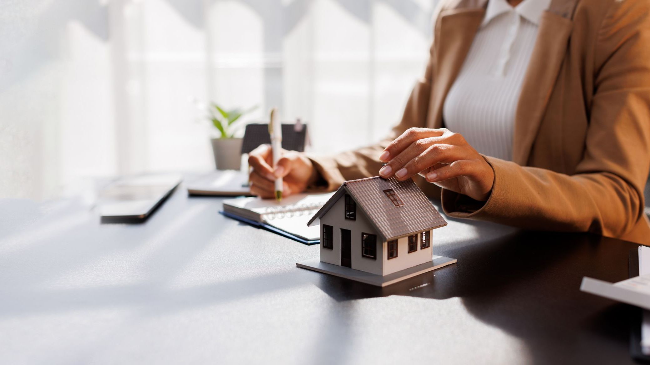 Real Estate Broker agent's signature on the contract finalized the mortgage agreement with hand on small house.