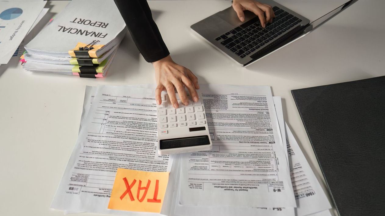 Businesswoman calculating finances using a calculator and managing tax paperwork.