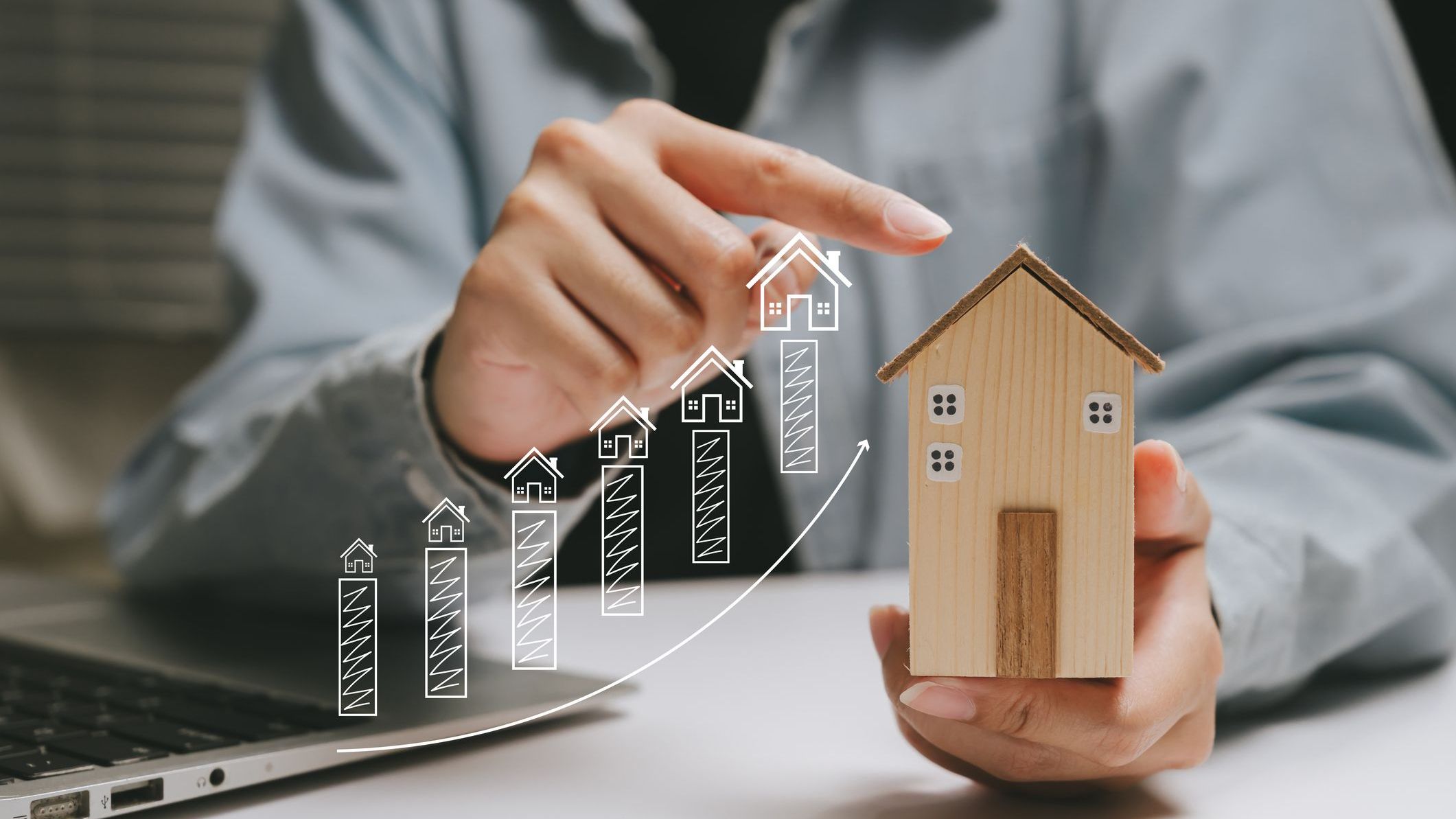 hand holding wooden house model with upward chart