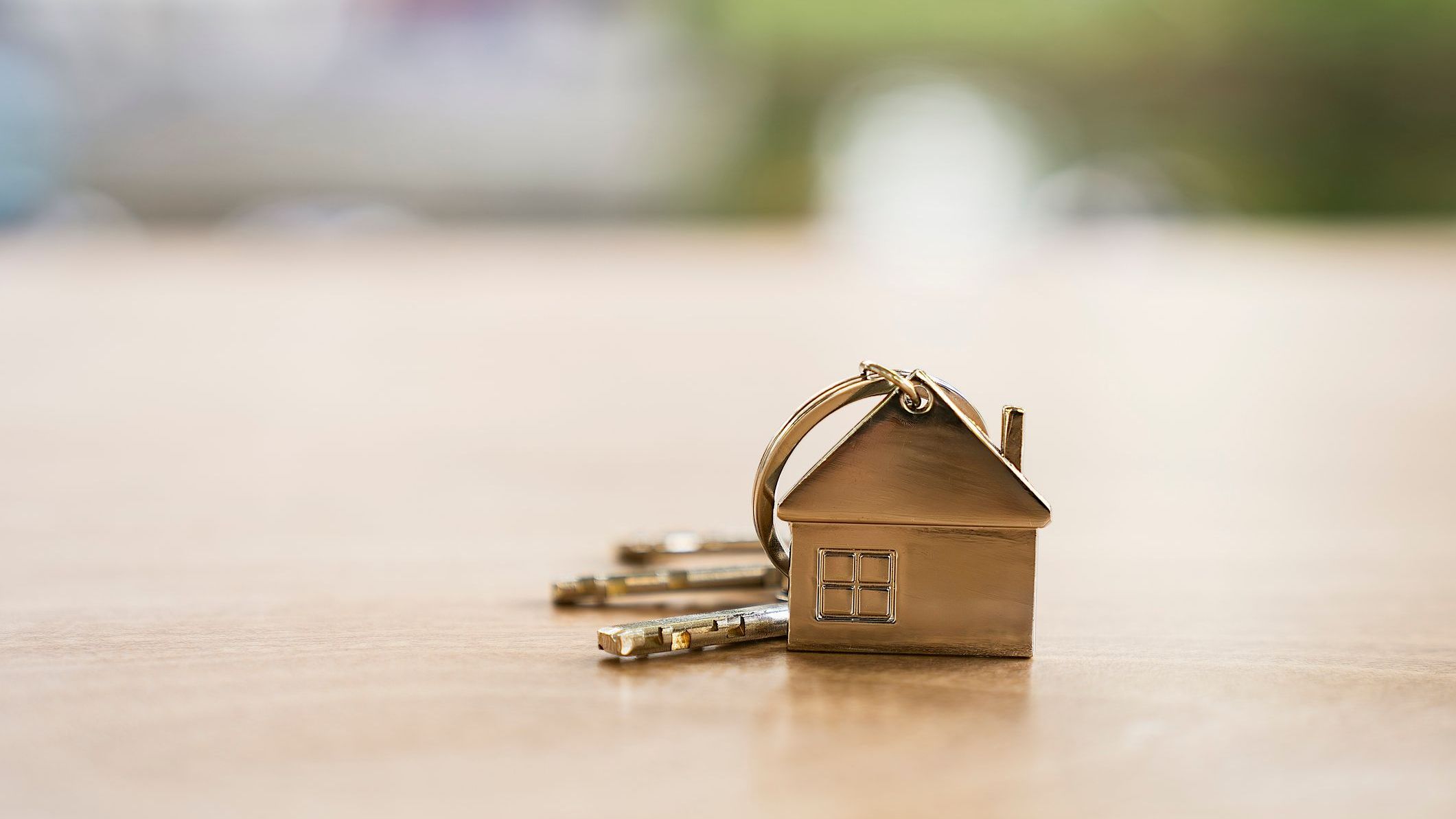 Close up of house keychain with keys on wooden table.