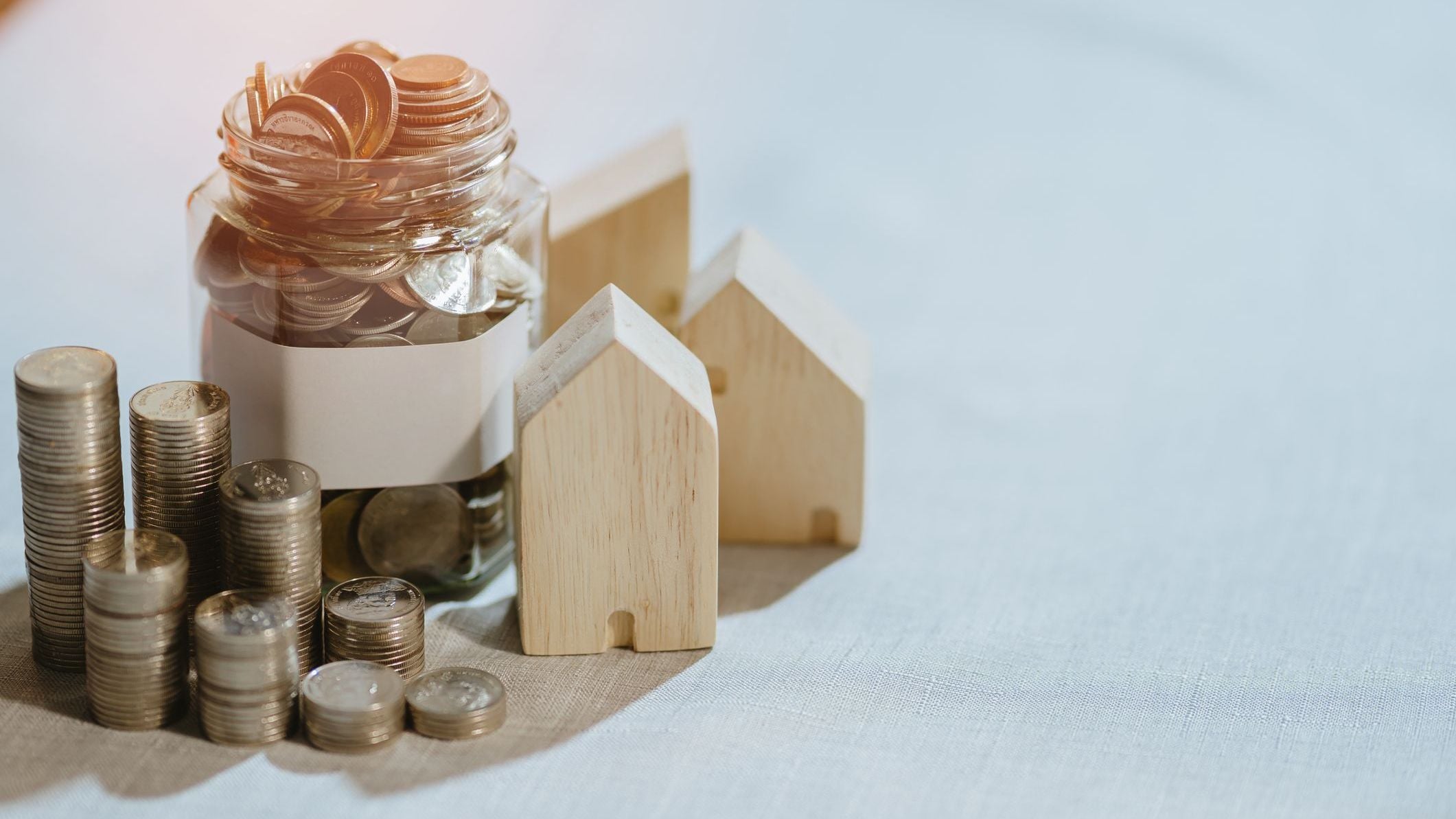 Saving money concept. Savings jar with coins and small house model for home finance and mortgage concept.